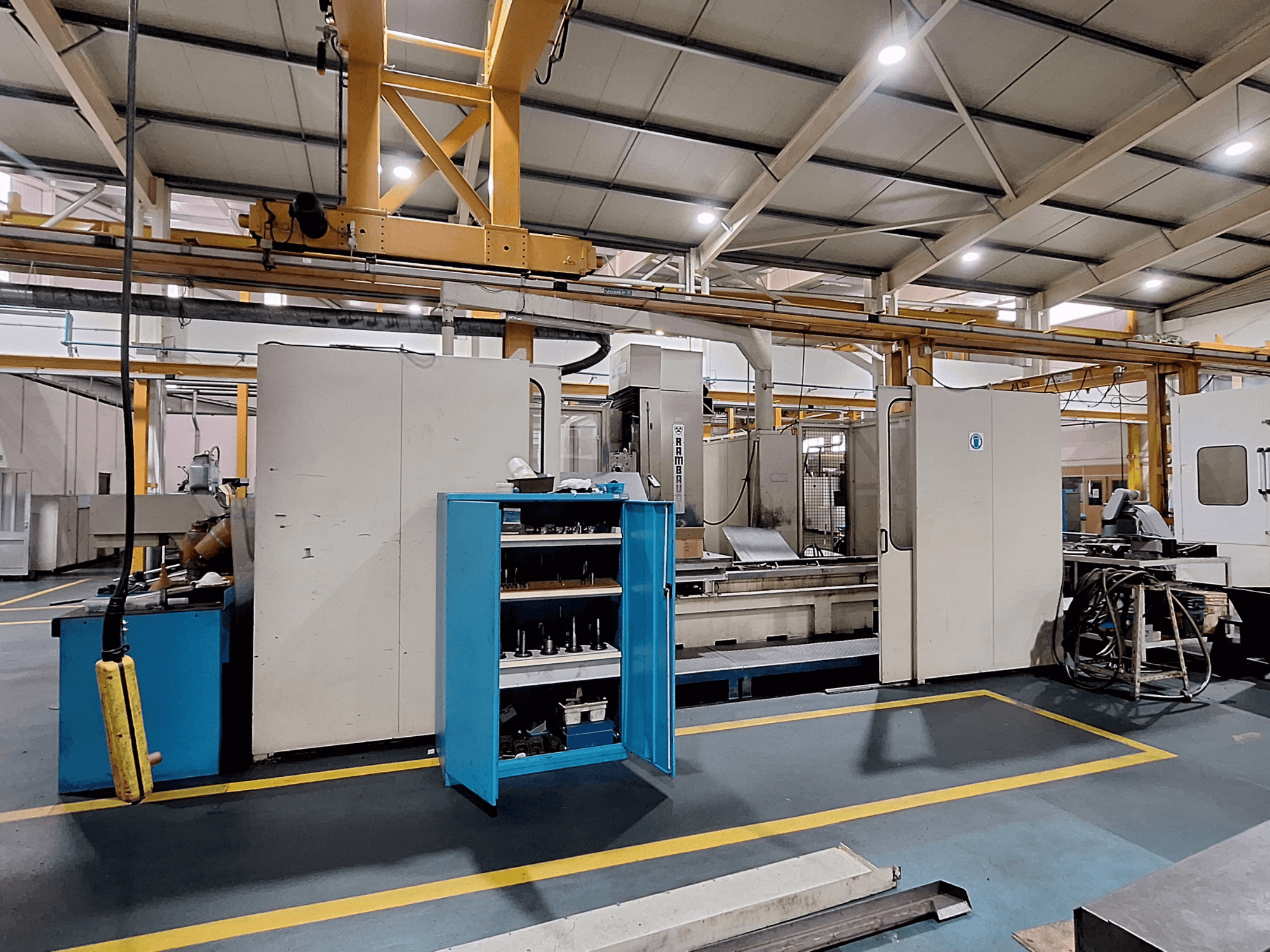 Rambaudi RX 1250 portálmarógép, elölnézetben szerszámtárolóval, tágas ipari munkaterületen.