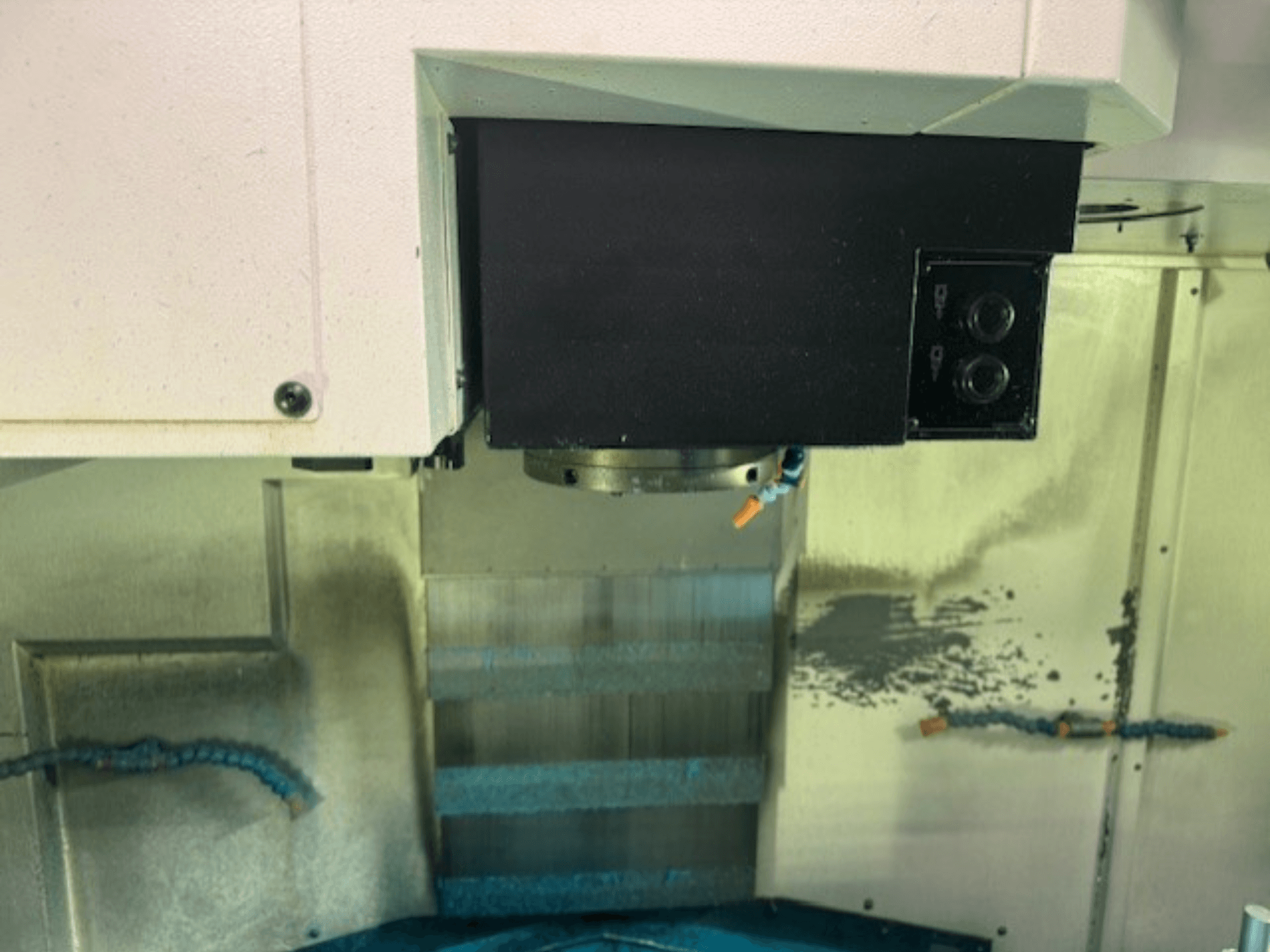 Közelkép egy CNC marógép vezérlőpaneléről és szerszámtartójáról, a márka részleteinek, a gomboknak és a munkafelületnek a bemutatásával.