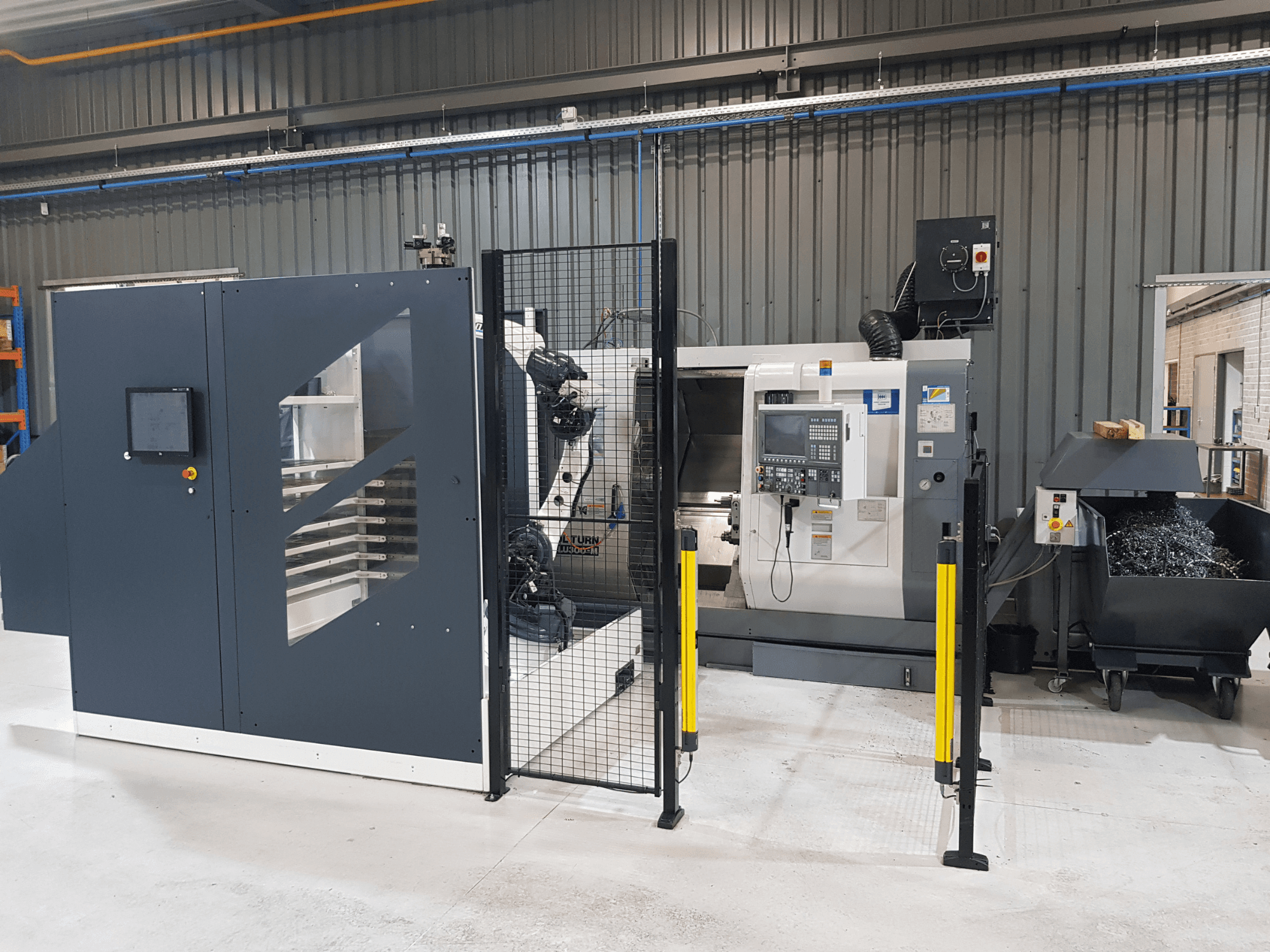 ALTURN automatizált esztergagép és CNC-gép gyári beállításban; elölnézetben a vezérlőpanel és a biztonsági kerítés látható.