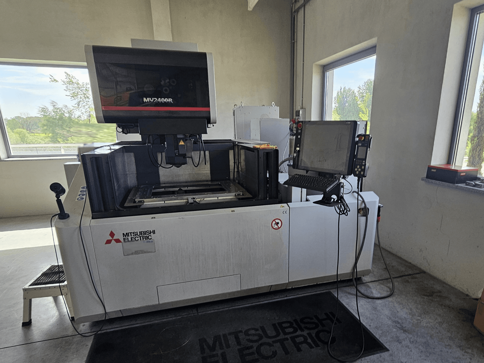 Mitsubishi MV2400R huzalos EDM gép egy műhelyben, érintőképernyős vezérlőpanellel és munkaterülettel.