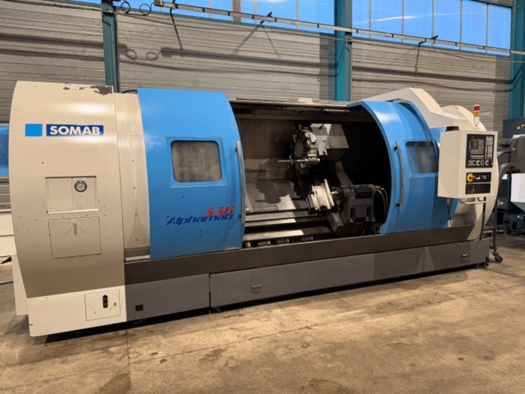SOMAB Alpha 336 CNC esztergagép, előlnézet, kék és szürke burkolattal és az oldalsó kezelőpanellel a működtetéshez.