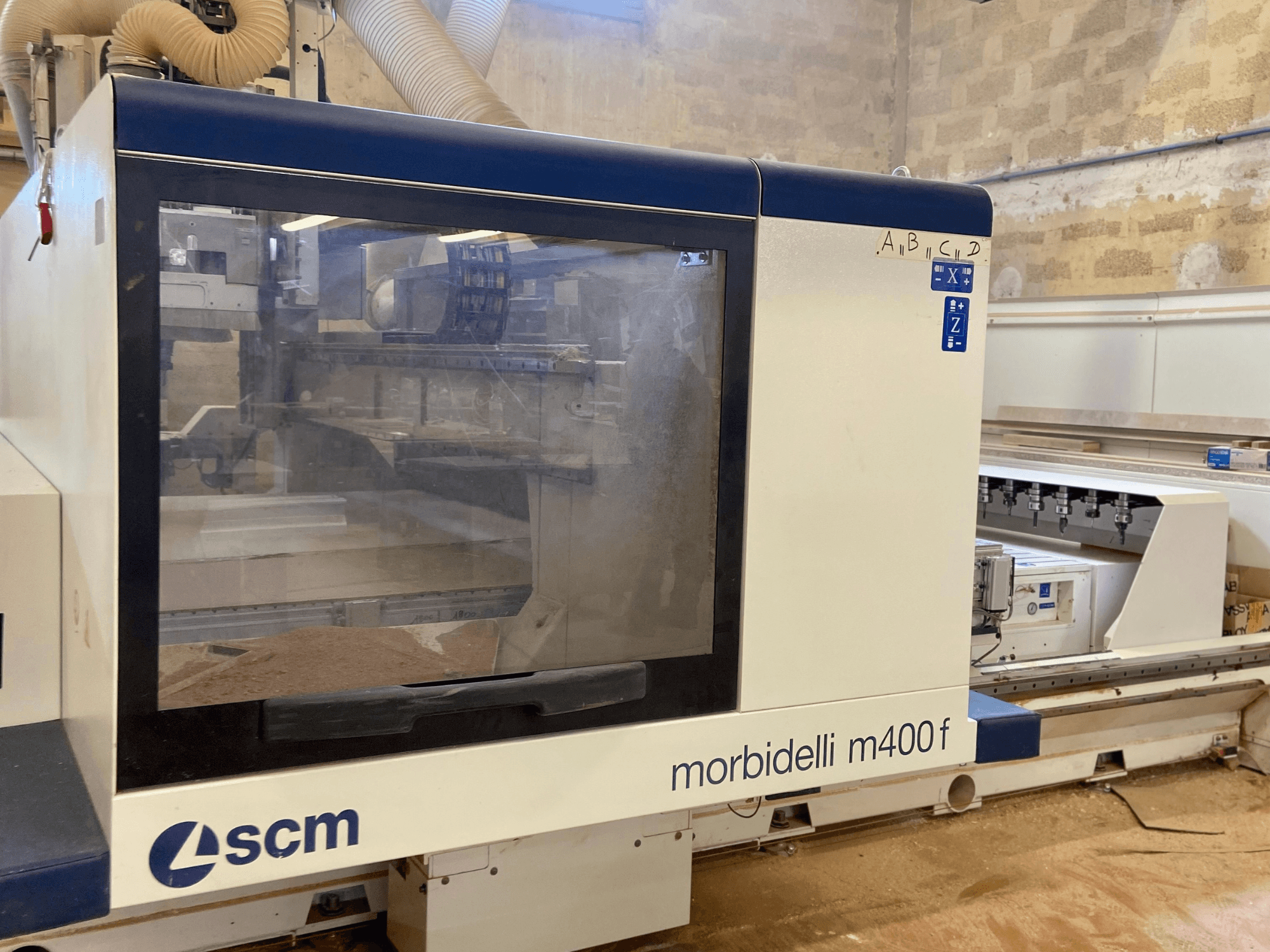 SCM Morbidelli M400F CNC-gép, elölnézetben, a vezérlőpanel és a padlón látható fűrészpor.