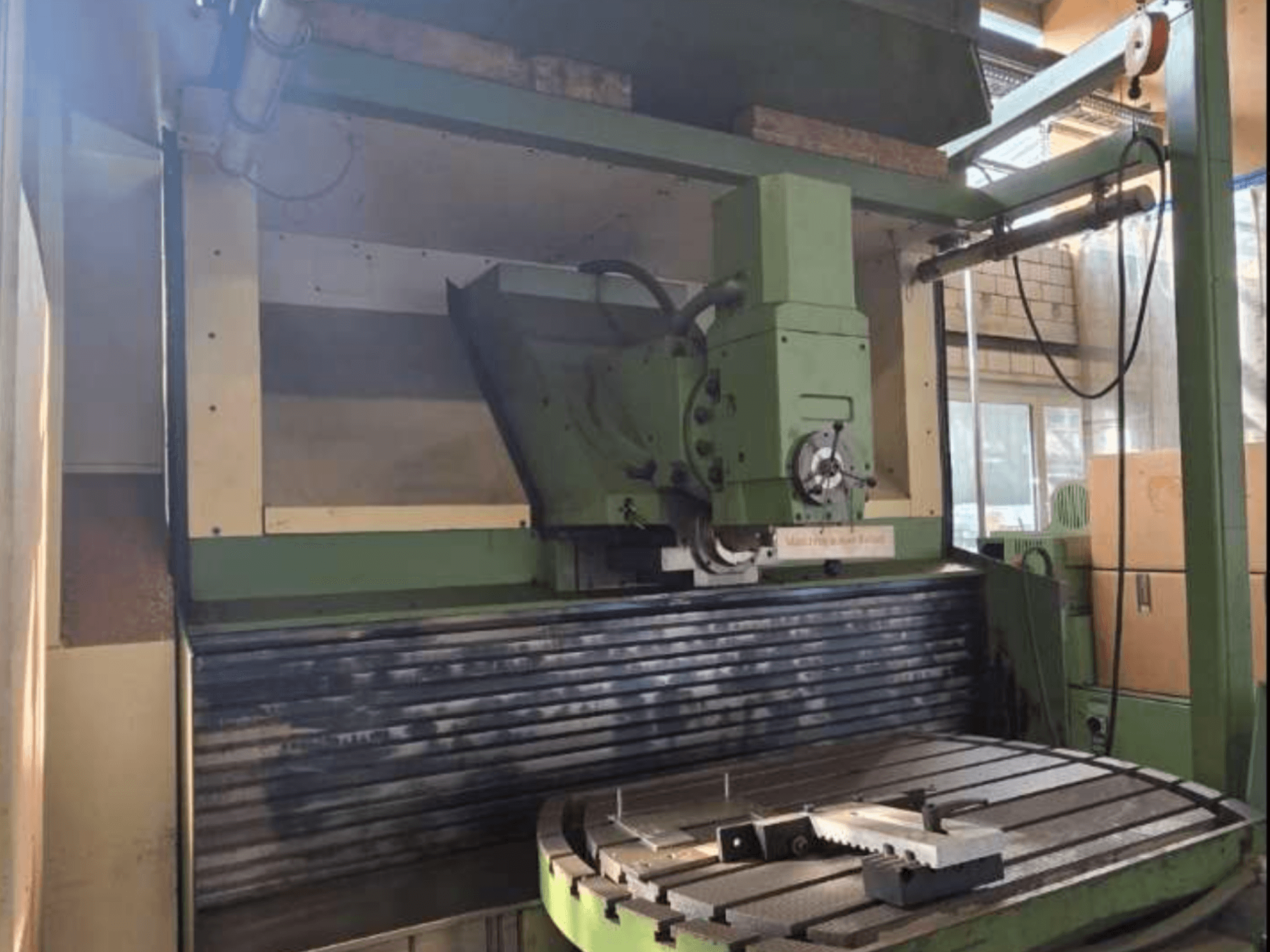 MAHO MH1000 C univerzális megmunkálóközpont elölnézetben, a zöld szerkezet, az orsó és a forgóasztal egy munkadarabbal.