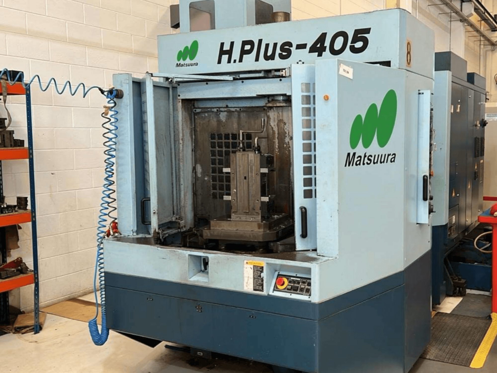 Egy Matsuura H.Plus 405 vízszintes megmunkálóközpont elölnézete nyitott ajtóval, amelyen látható a munkaterület és a vezérlőpanel.