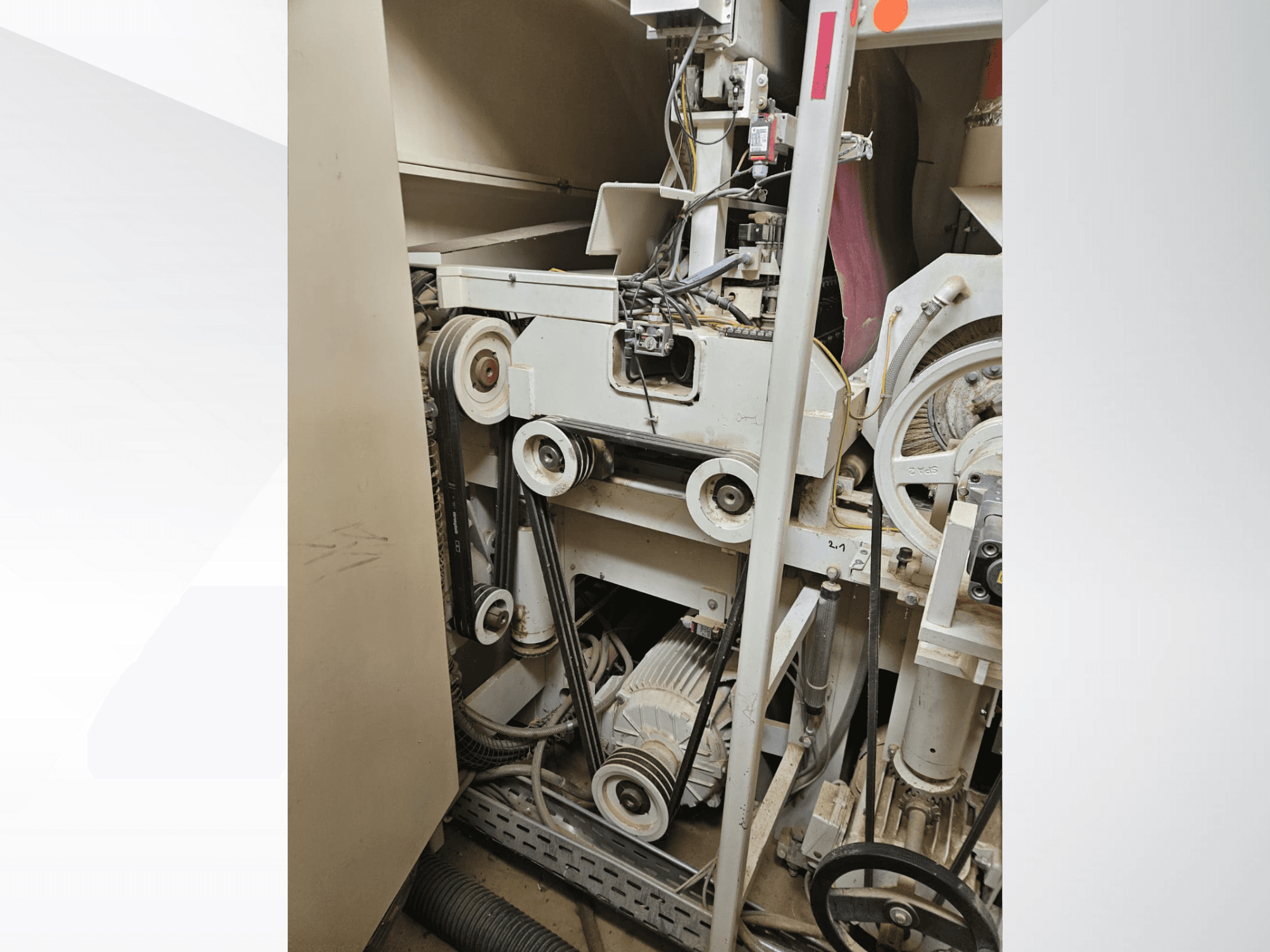 Ipari gép belseje szíjakkal és csigákkal, motorral és vezetékekkel, oldalról nézve.