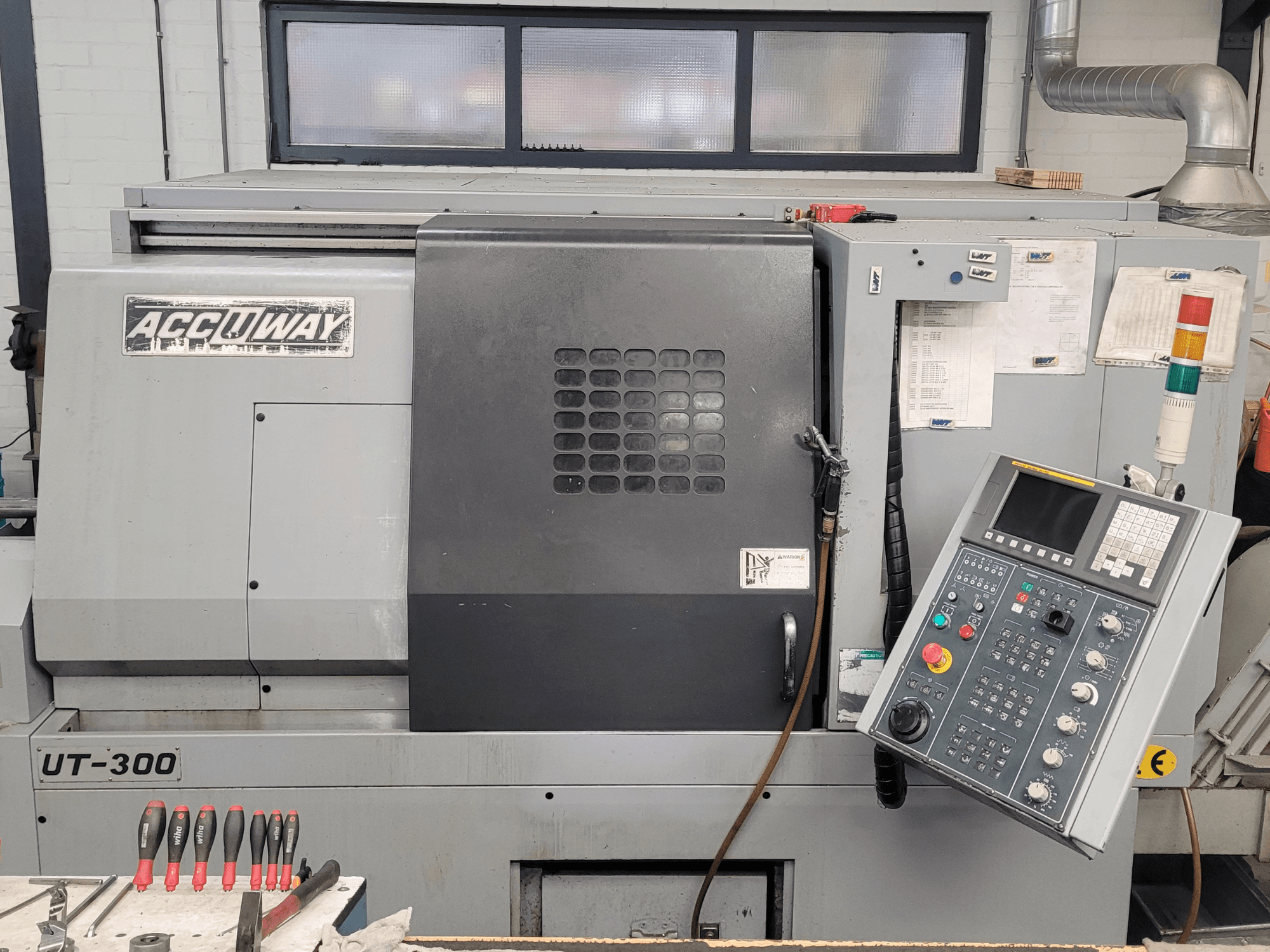 Accuway UT-300 CNC gép elölnézetben, kezelőpanellel és különböző kezelőgombokkal, műhelyben.