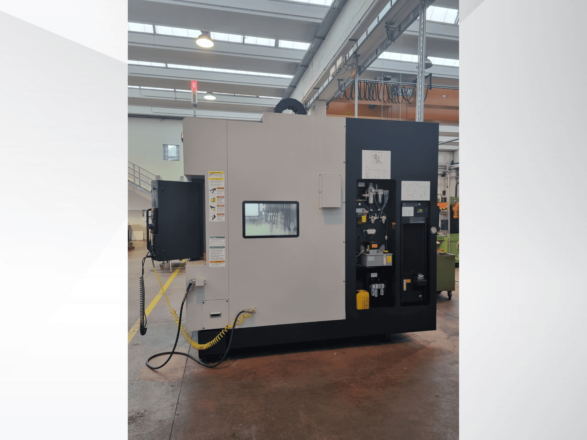 Ipari gép oldalnézetből, vezérlőpanel gombokkal, kijelzőkkel és biztonsági figyelmeztető címkével.