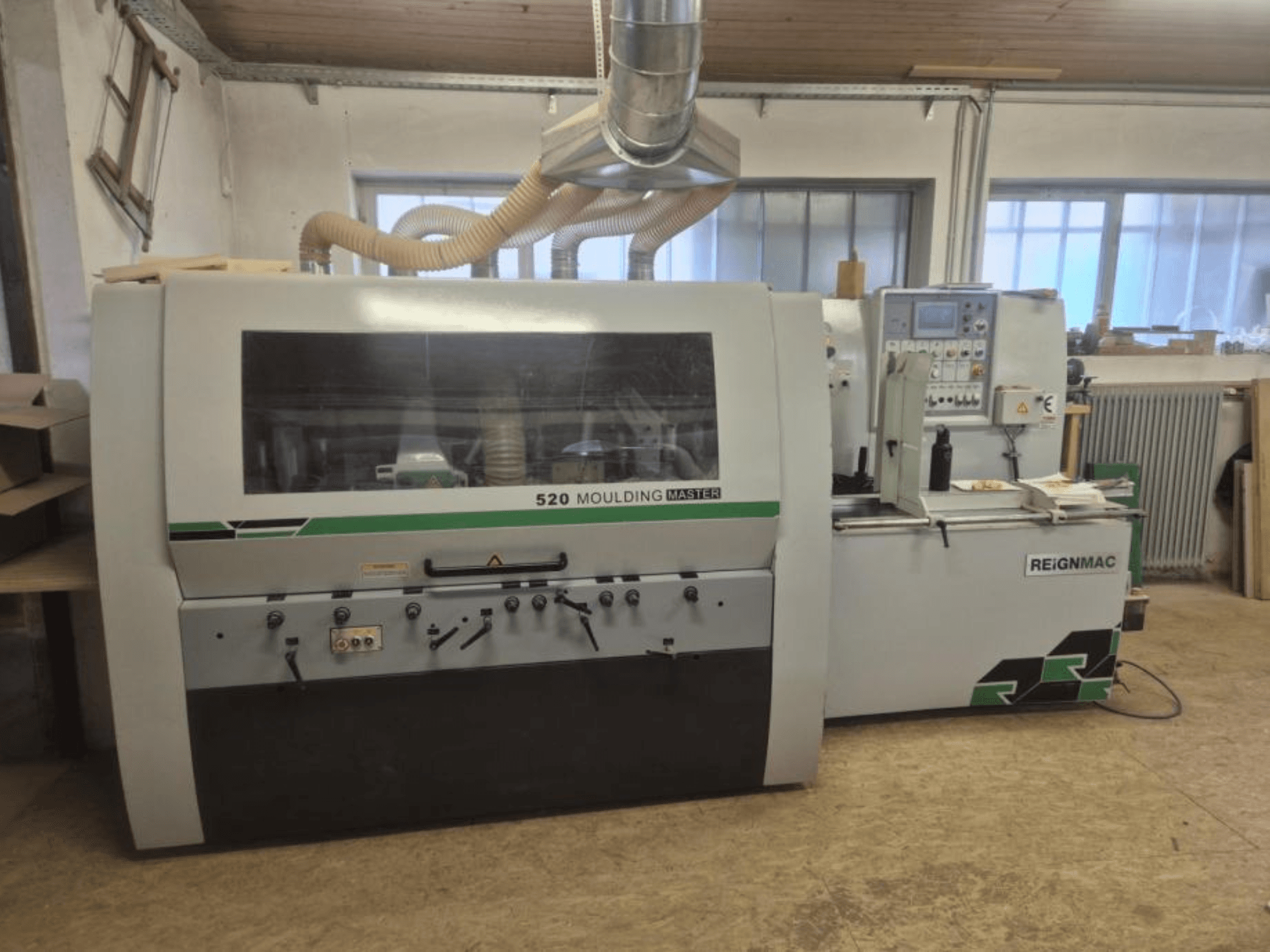 A REIGNMAC 520 MOULDING MASTER faipari gyalugép elülső nézete, a kezelőpanel, az adagolóhengerek és a porelszívó rendszer bemutatása.