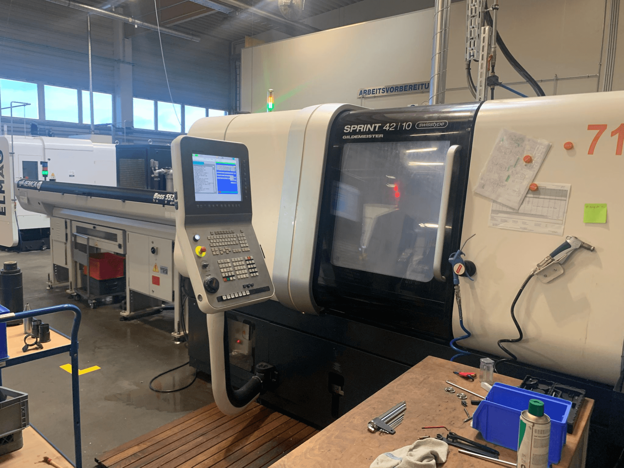 DMG MORI Sprint 42/10 lineáris svájci típusú esztergagép, előlnézet, vezérlőpanel és munkaterület-zsúfoltság.