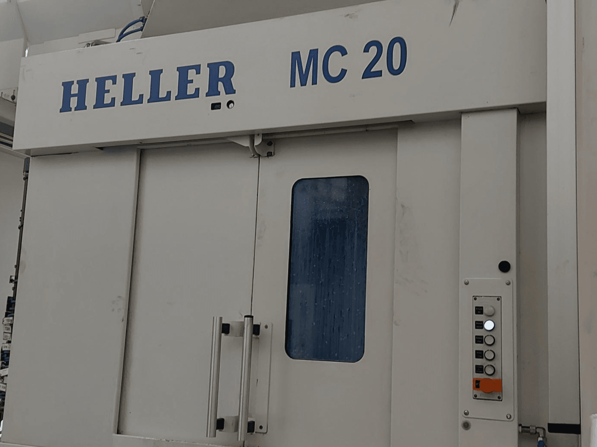 A HELLER MC 20 vízszintes megmunkálóközpont elülső nézete a kezelőpanel és az elülső ablak látható.