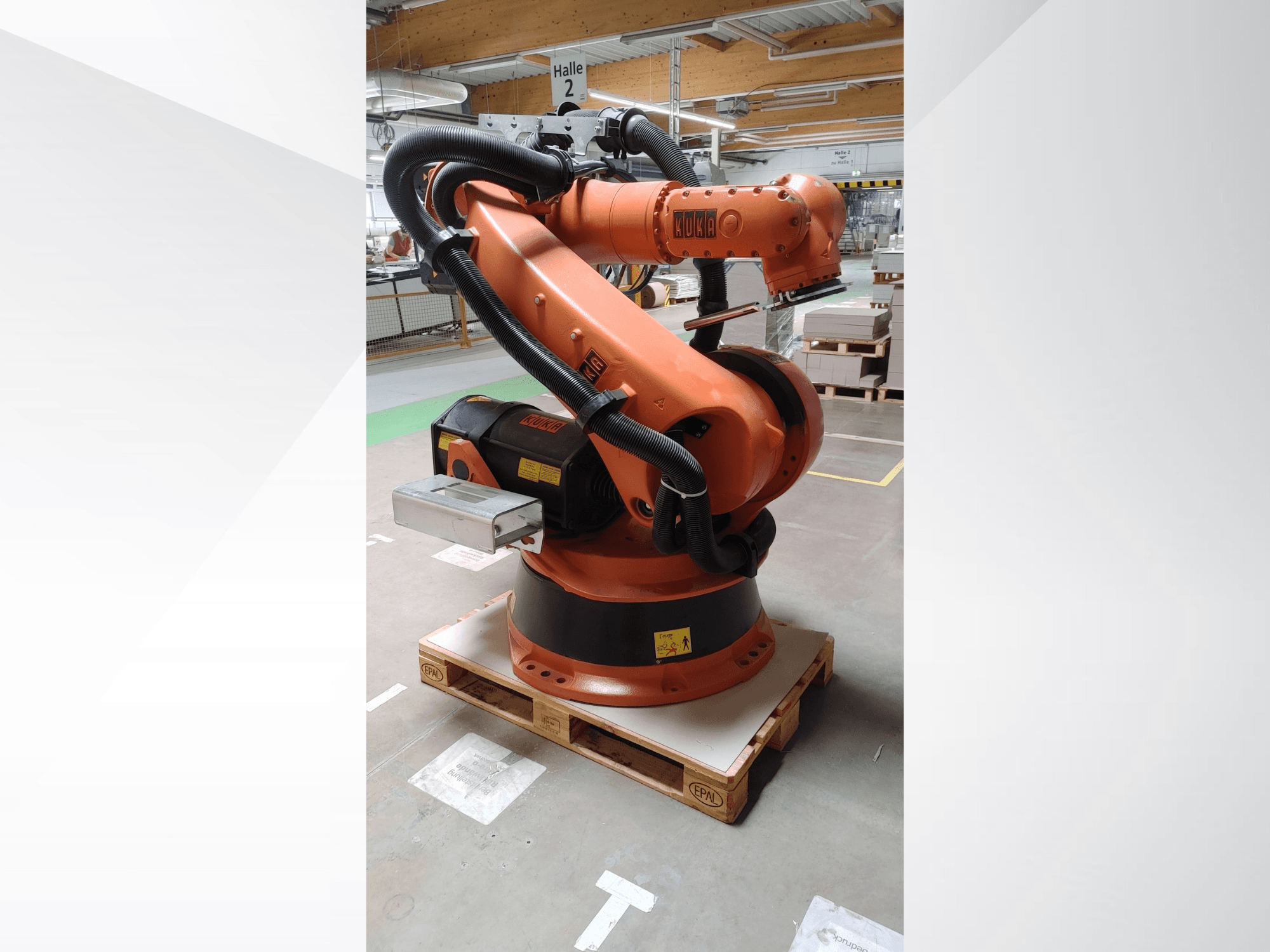 KUKA KR140-3 COMP robotkar narancssárga színben, elölnézetben, fa raklapon, ívelt karral és vezérlődobozzal.