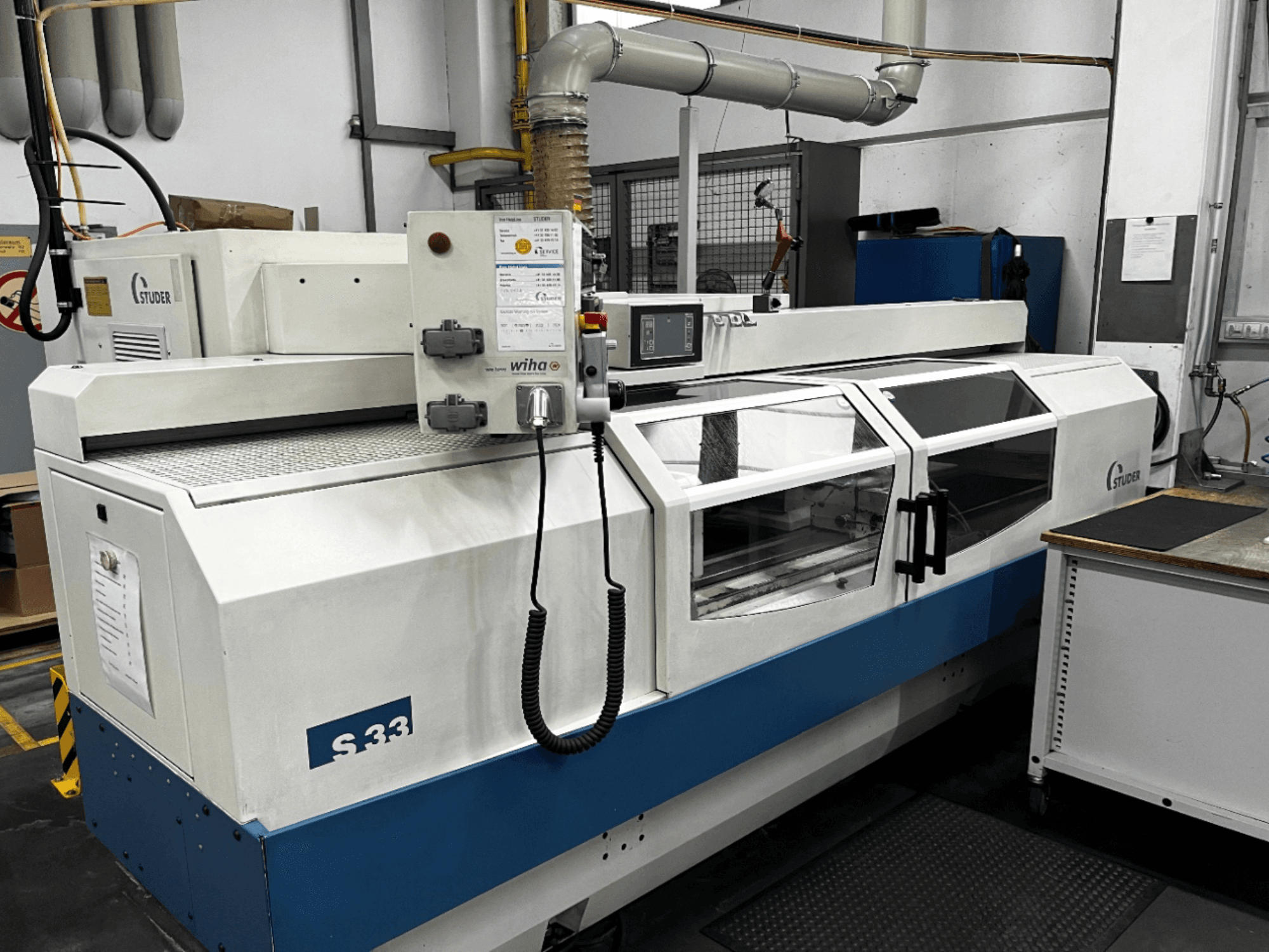 STUDER S33 CNC hengeres köszörűgép, elölnézet; vezérlőpanel és biztonsági üvegajtók. Ipari környezet.