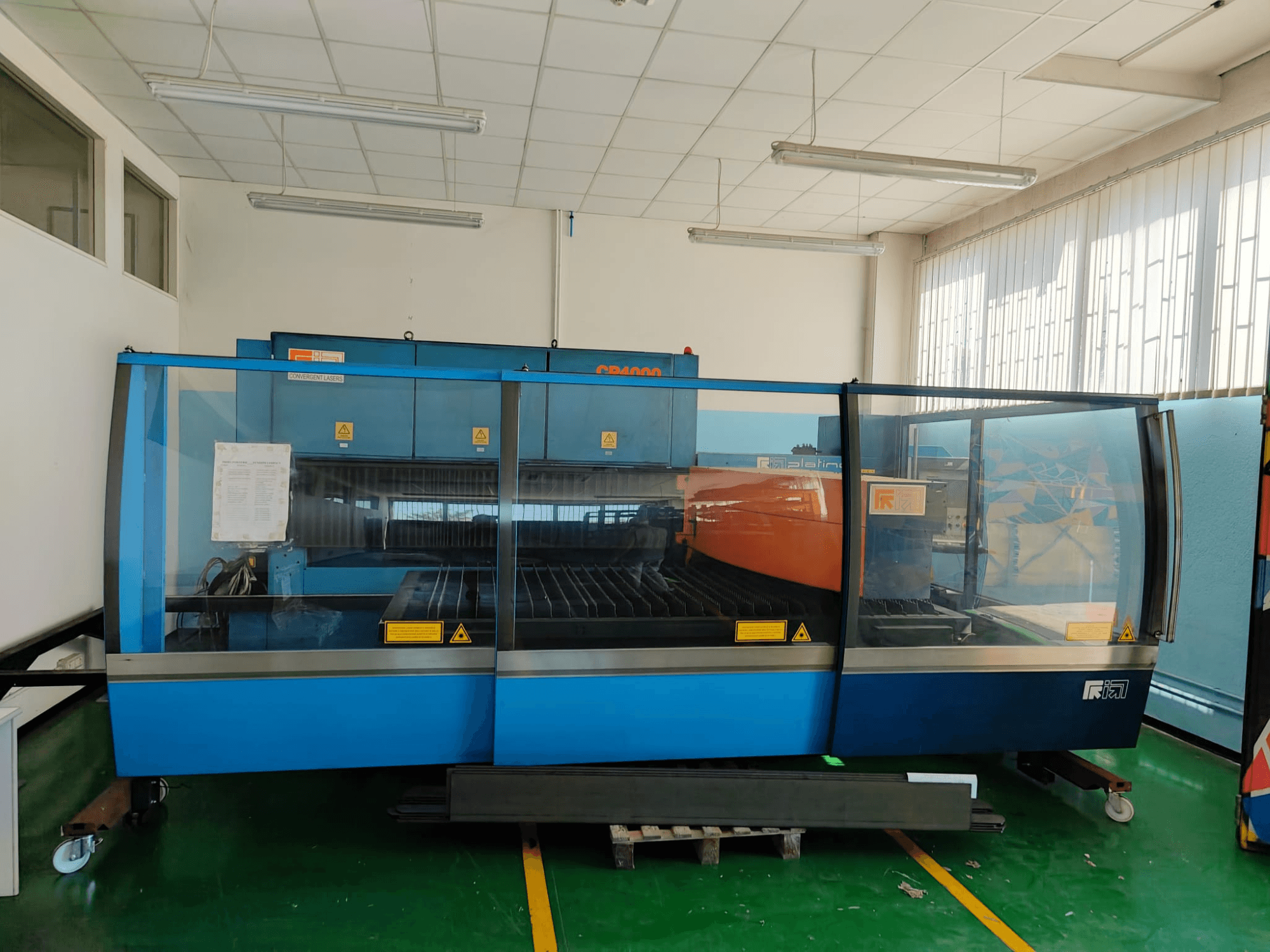 A CONVERGENT LASERS CP4000 CO₂ lézervágó gép elölnézete, kék és narancssárga színű kialakítással, jól megvilágított műhelykörnyezetben.