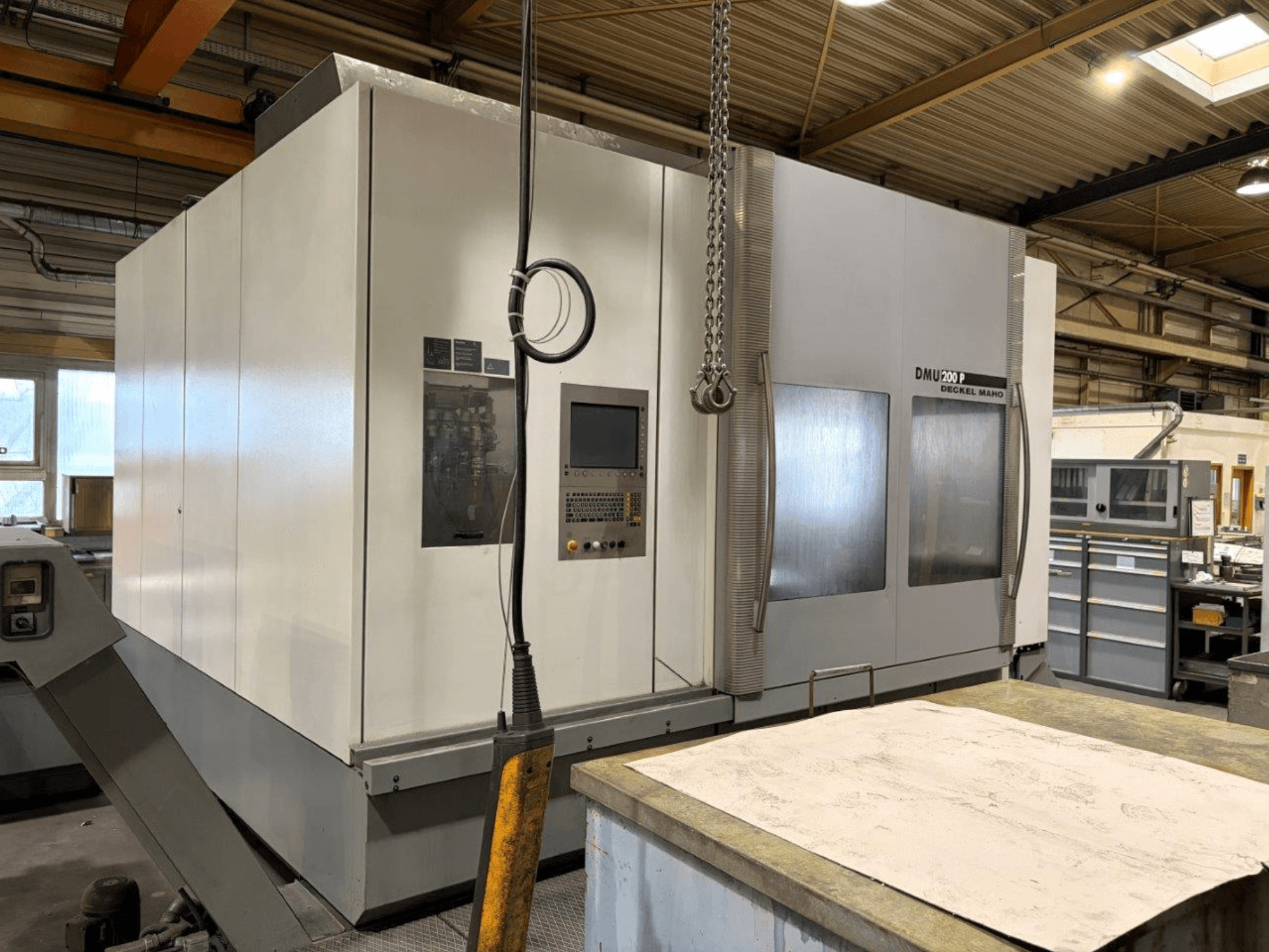 DMG MORI DMU 200 univerzális megmunkálóközpont egy műhelyben, elölnézetben, a kezelőpanel és a külső jellemzők bemutatásával.