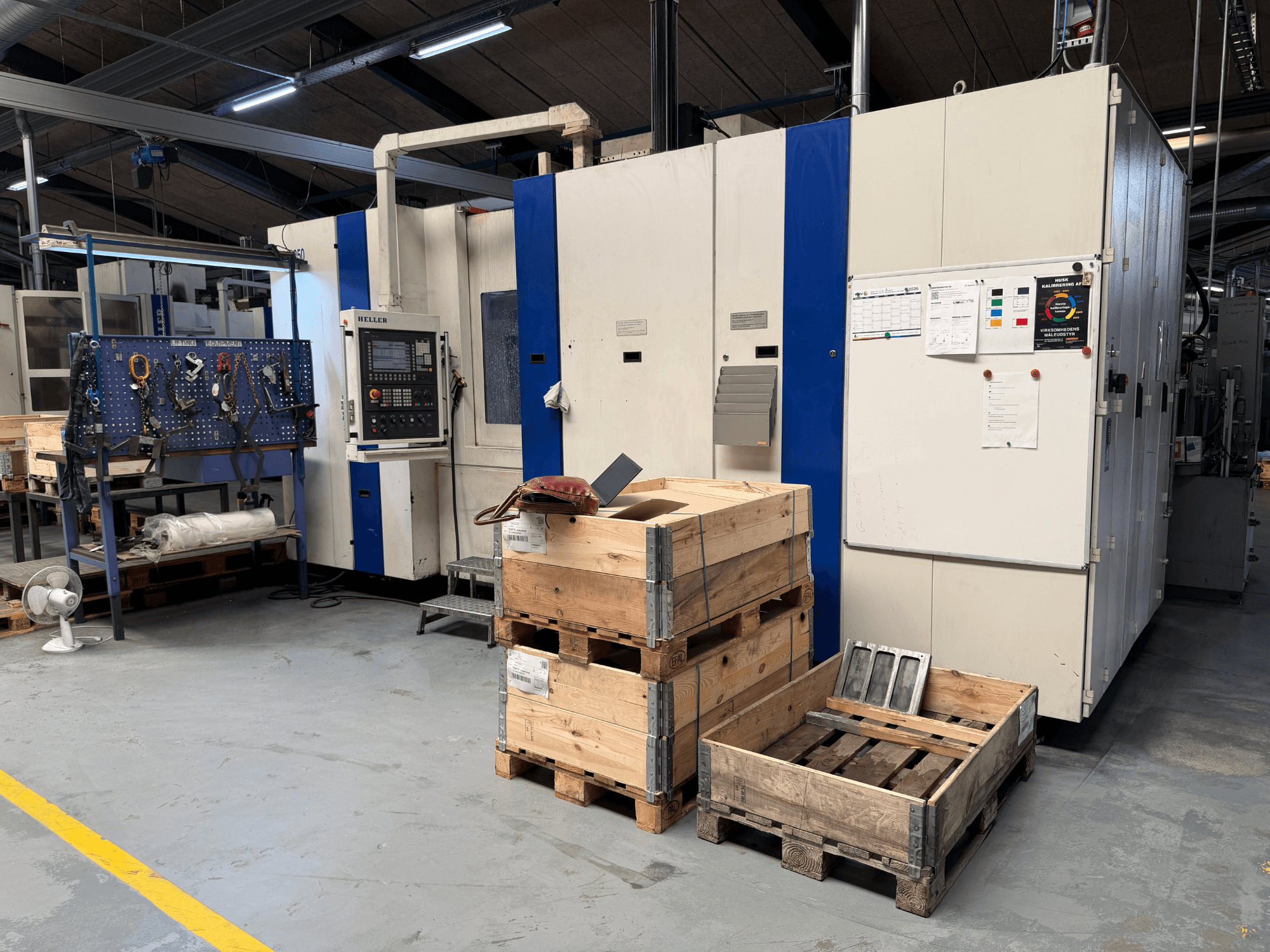 HORIZONTÁLIS GÉPESÍTŐKÖZPONT HELLER MCH 250 a műhelyben, oldalnézet, láthatóak a fa raklapok és a szerszámtartó állvány.