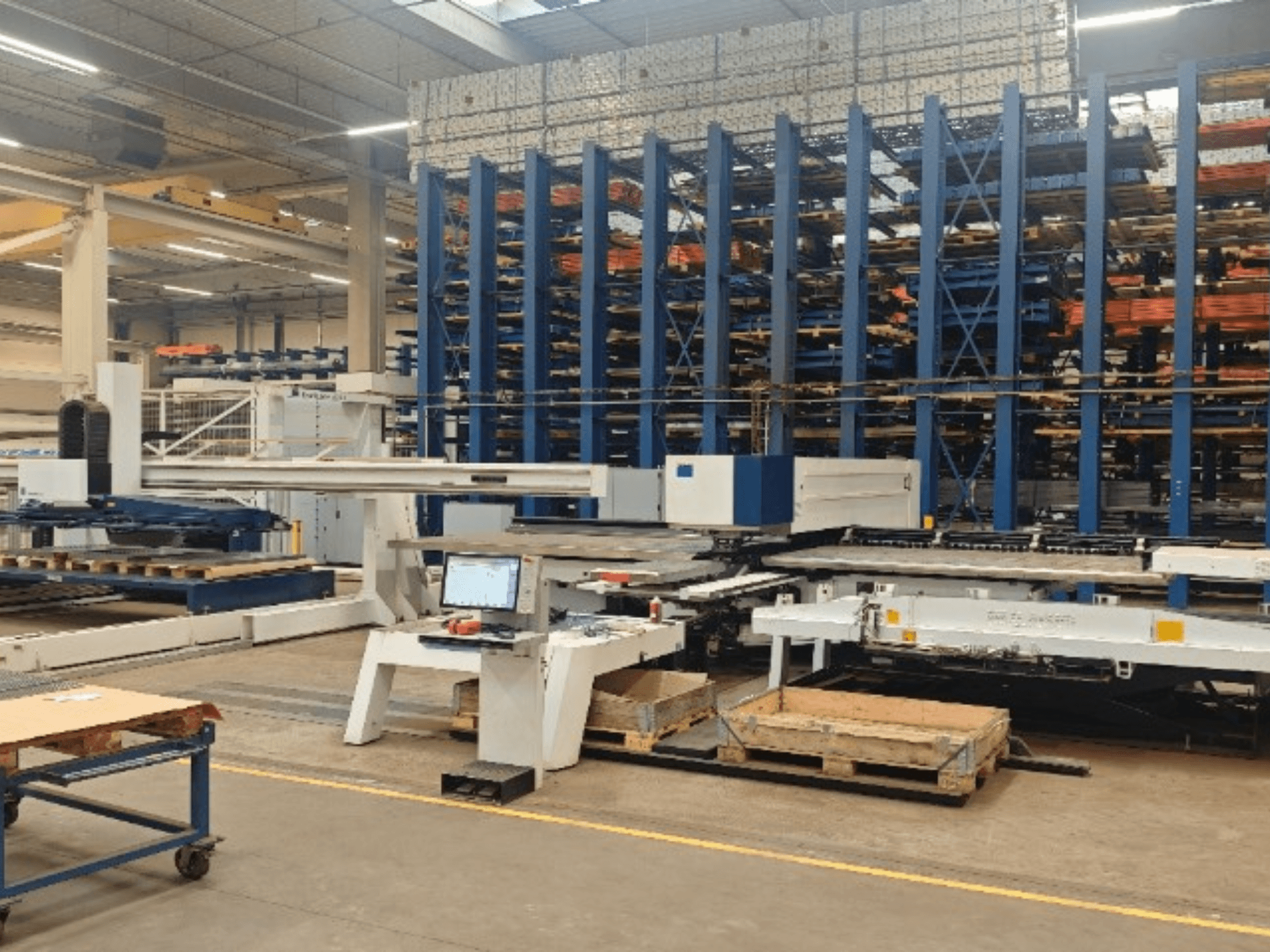 TRUMPF TruPunch 5000 S12 CNC-lyukasztógép egy műhelyben, elölről nézve, a vezérlőpanellel és a tárolóterülettel együtt.