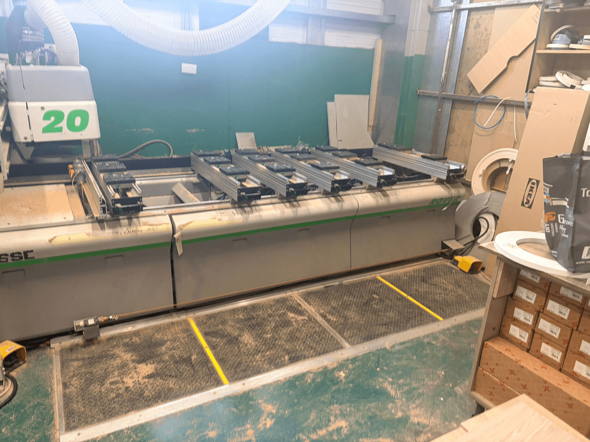 CNC faipari megmunkálóközpont BIESSE ROVER 20, elölnézetben, a sínrendszerrel, a vezérléssel és a fűrészporral a felületen.