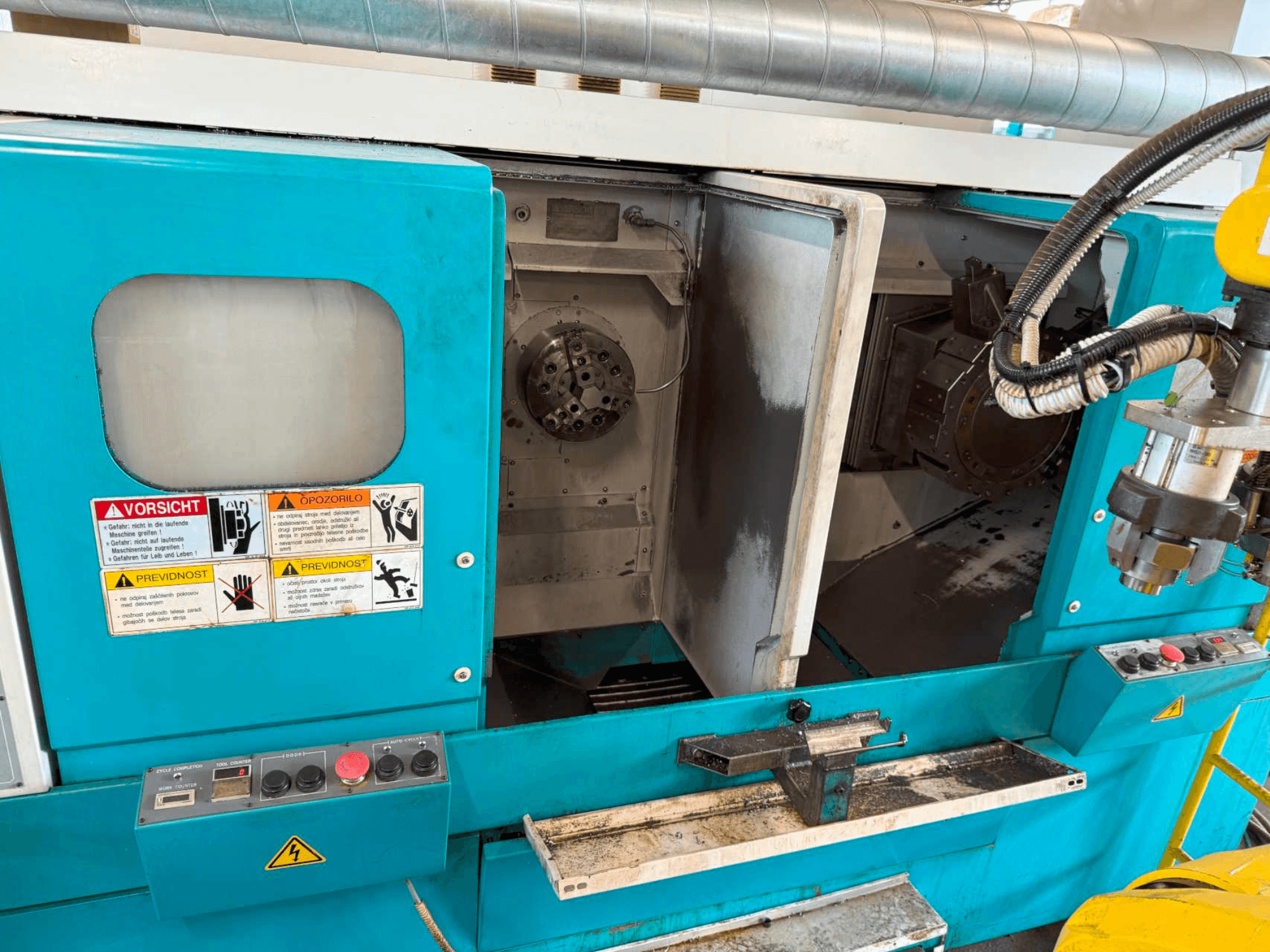 DOOSAN H310T vízszintes esztergagép, elölnézetben a vezérlőpanel és az orsó területe a biztonsági figyelmeztetésekkel.