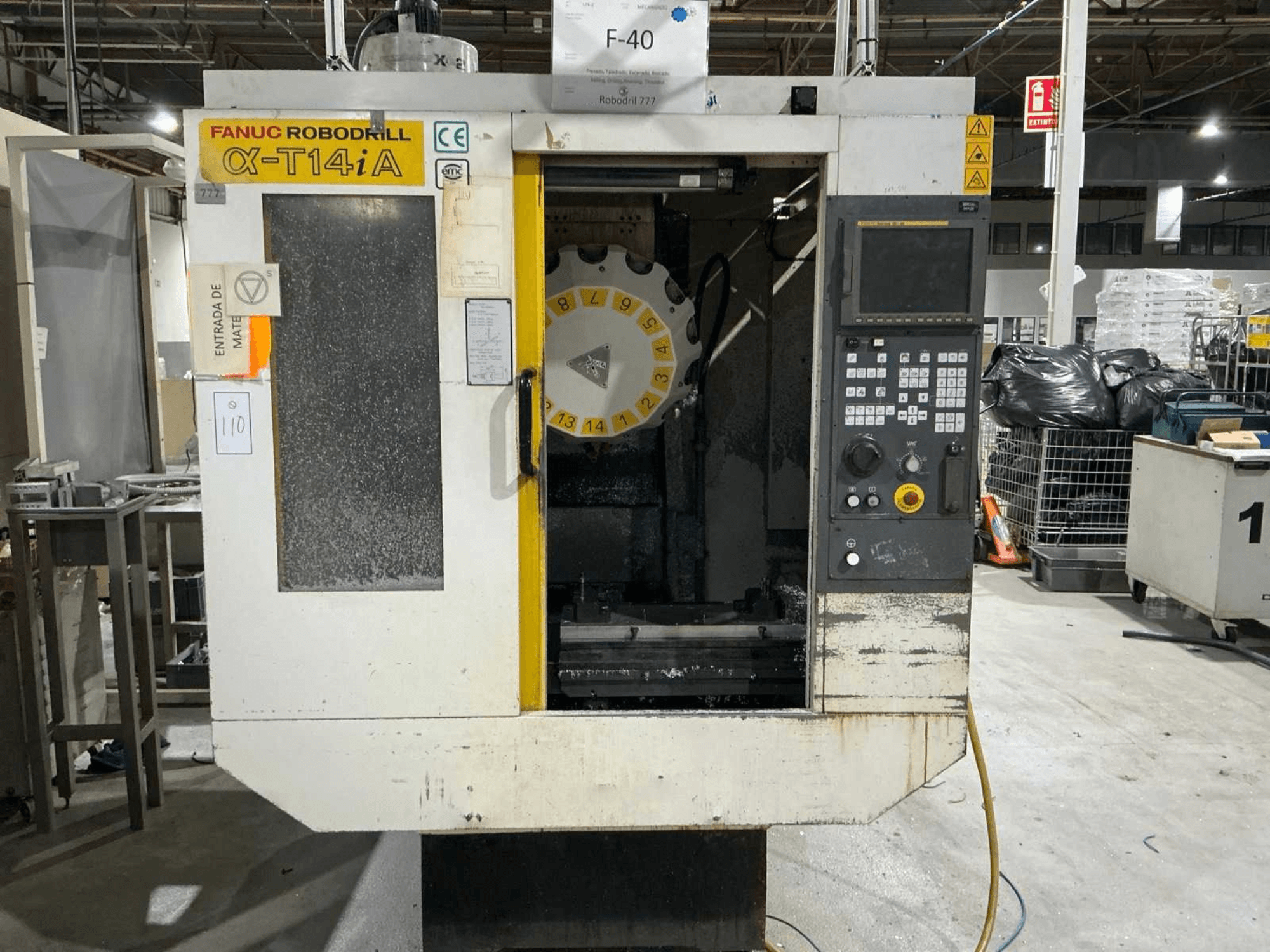 FANUC ROBODRILL α-T14iB függőleges megmunkálóközpont, elölnézetben a vezérlőpanel és a szerszámkarusszel.