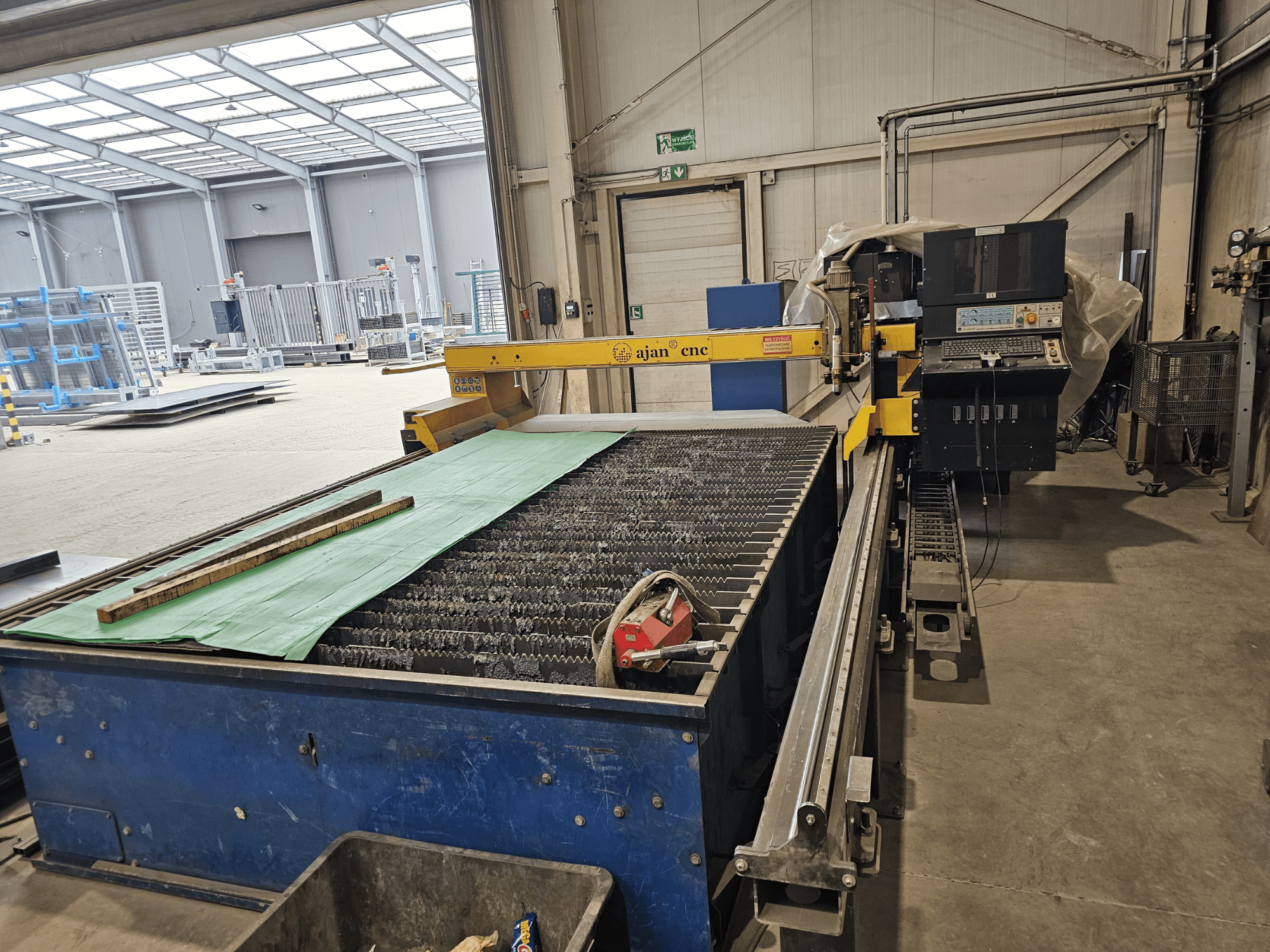 AJAN PP16011 Automatikus plazmavágó gép oldalnézetben, vágóasztallal és vezérlőpanellel, műhelykörnyezetben.