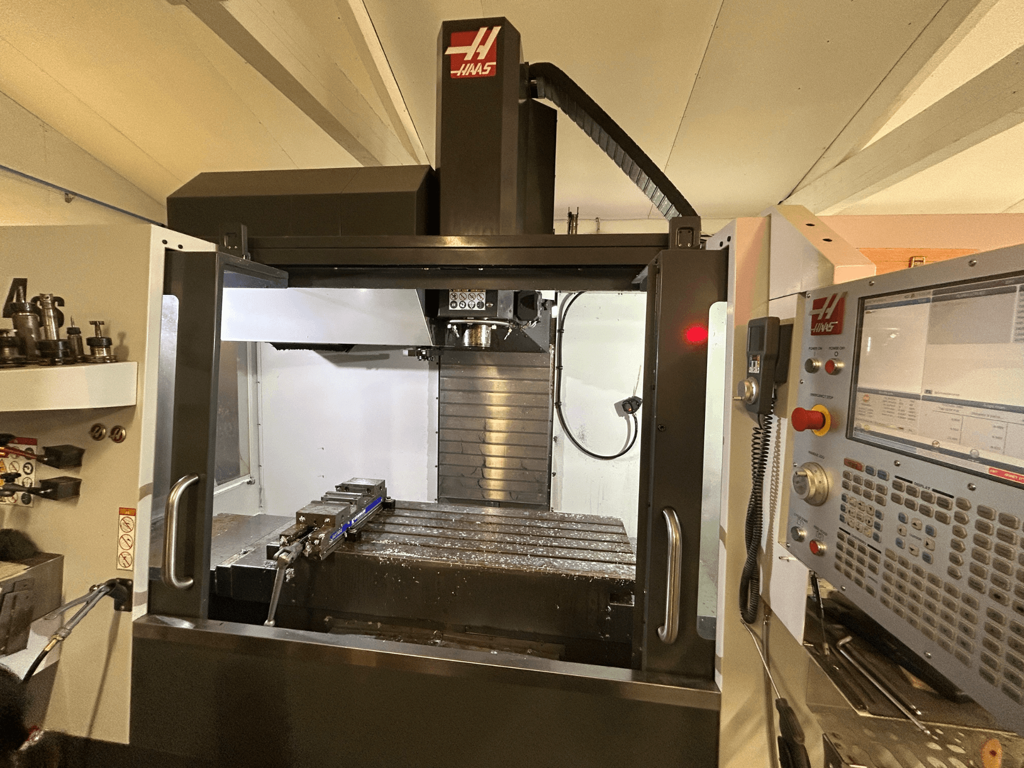 HAAS VF-4SS függőleges megmunkálóközpont, elölnézet, a vezérlőpanel, a szerszámtartó és a fémforgácsokkal teli munkaterület.