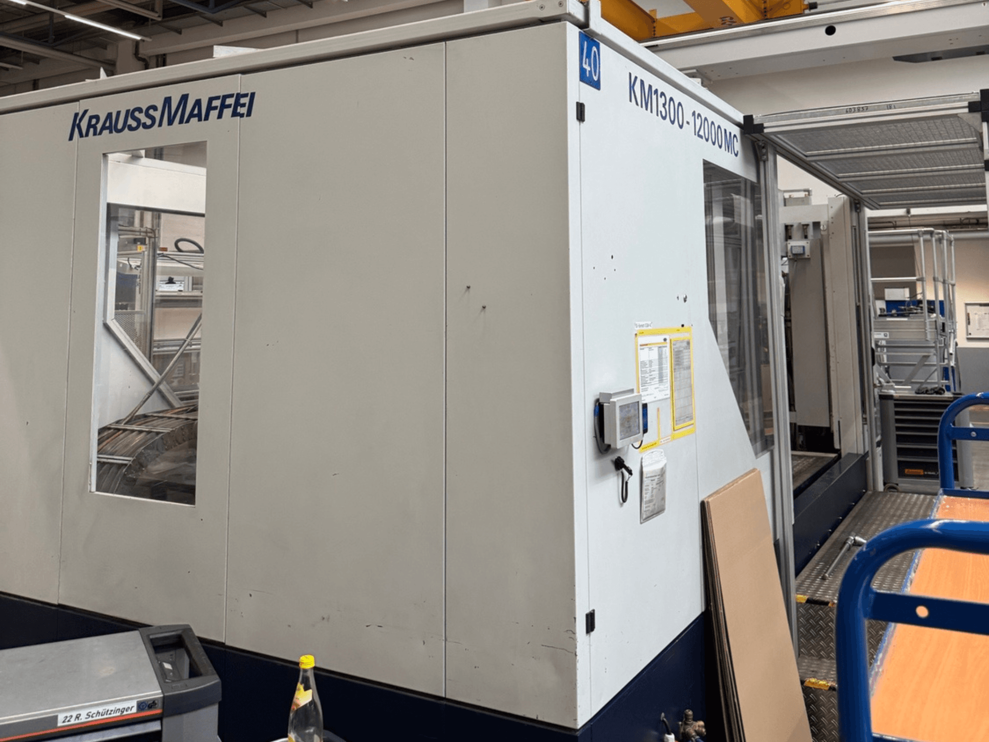 Krauss Maffei KM1300-12000 MC hidraulikus fröccsöntőgép, oldalnézet, a kezelőpanel és a kezelőtér bemutatása.
