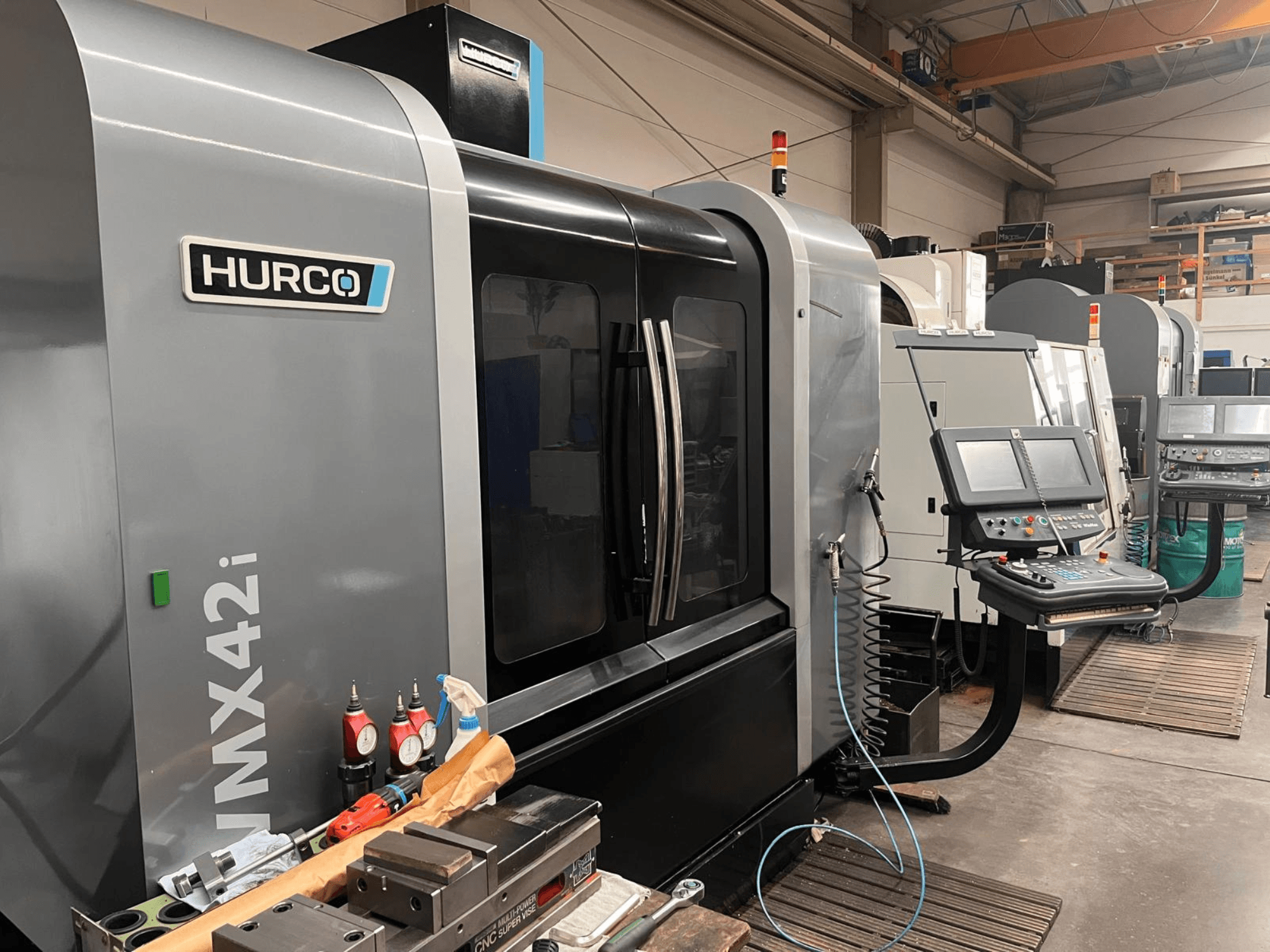 Hurco VMX42i CNC-gép egy műhelyben, elölnézetben, a vezérlőpanel és a különböző szerszámok a munkapadon.