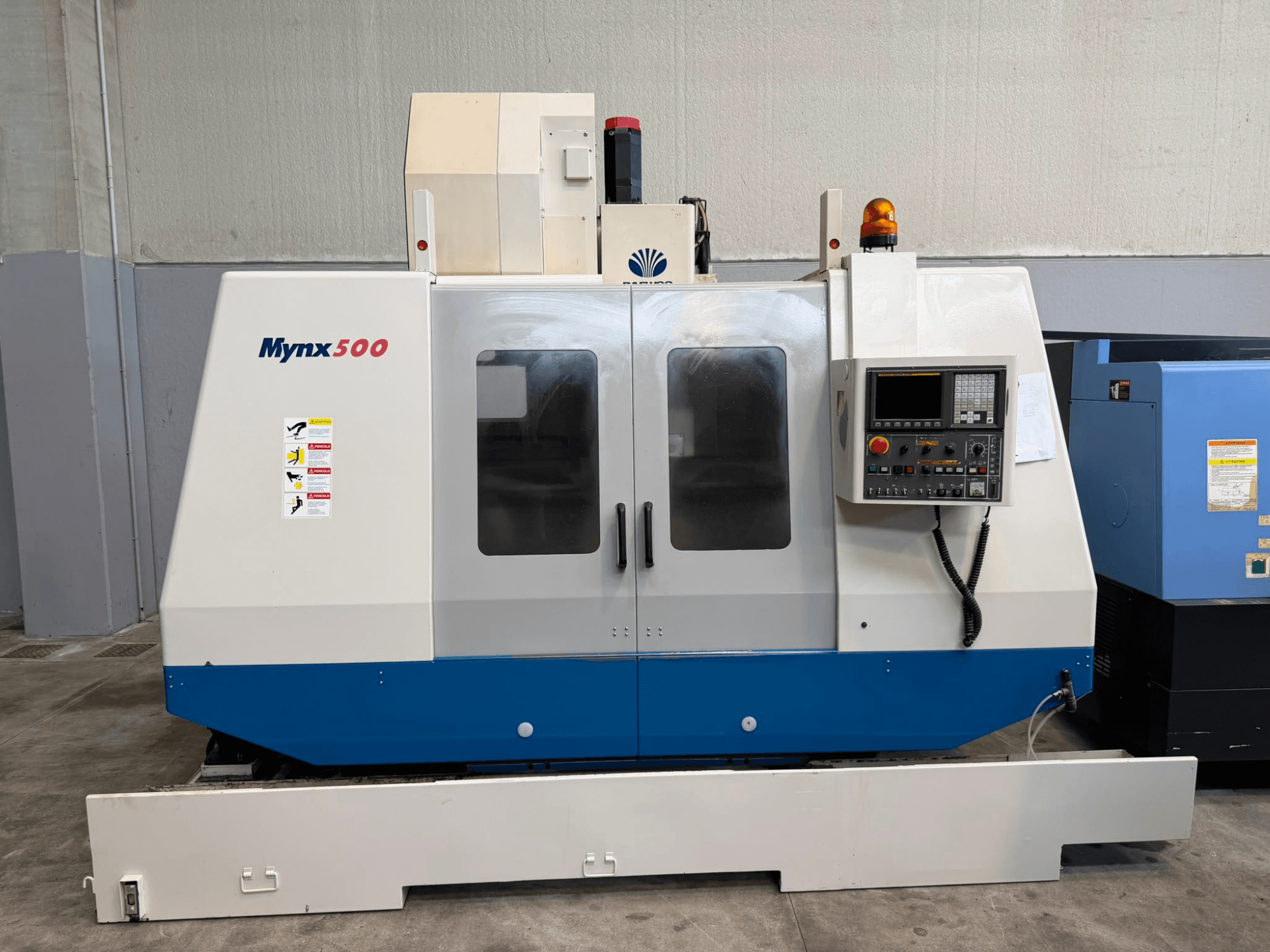 A DAEWOO MYNX 500 függőleges megmunkáló központ elölnézete a vezérlőpanellel, a biztonsági lámpákkal és az átlátszó ajtókkal.