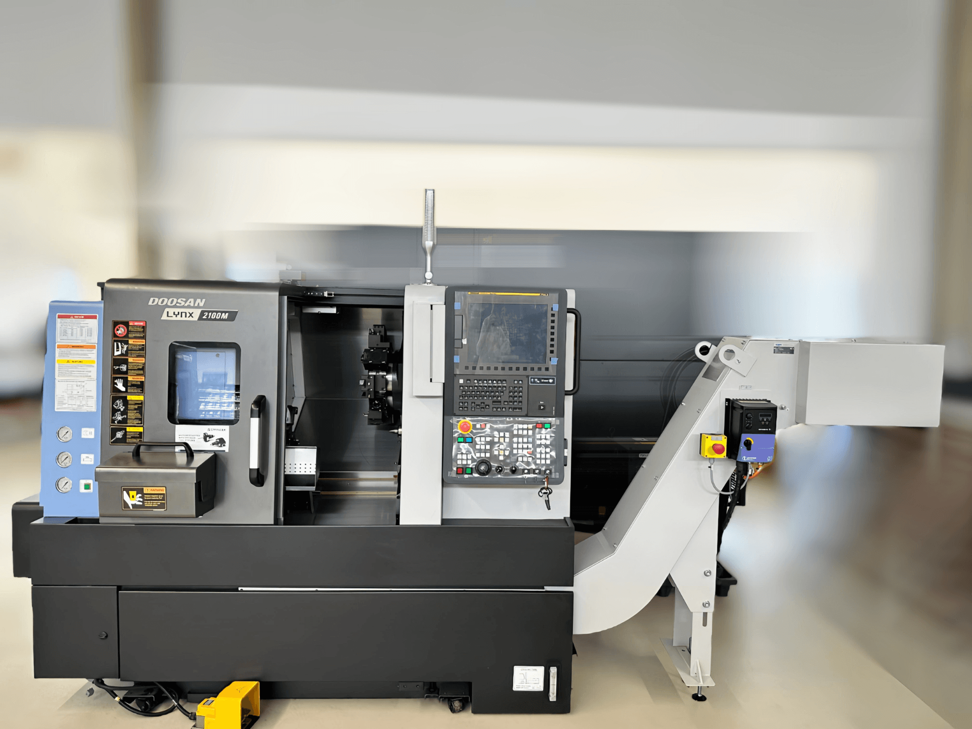 A DN SOLUTIONS LYNX 2100MB vízszintes esztergagép elülső nézete, a vezérlőpanel és a munkaterület részleteivel.