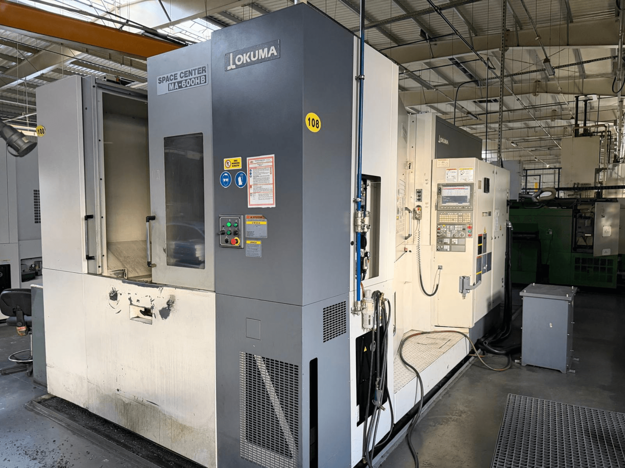 Okuma MA-600 HB vízszintes megmunkálóközpont, elölnézet, a vezérlőpanel és a vágási terület látható kopásnyomokkal.