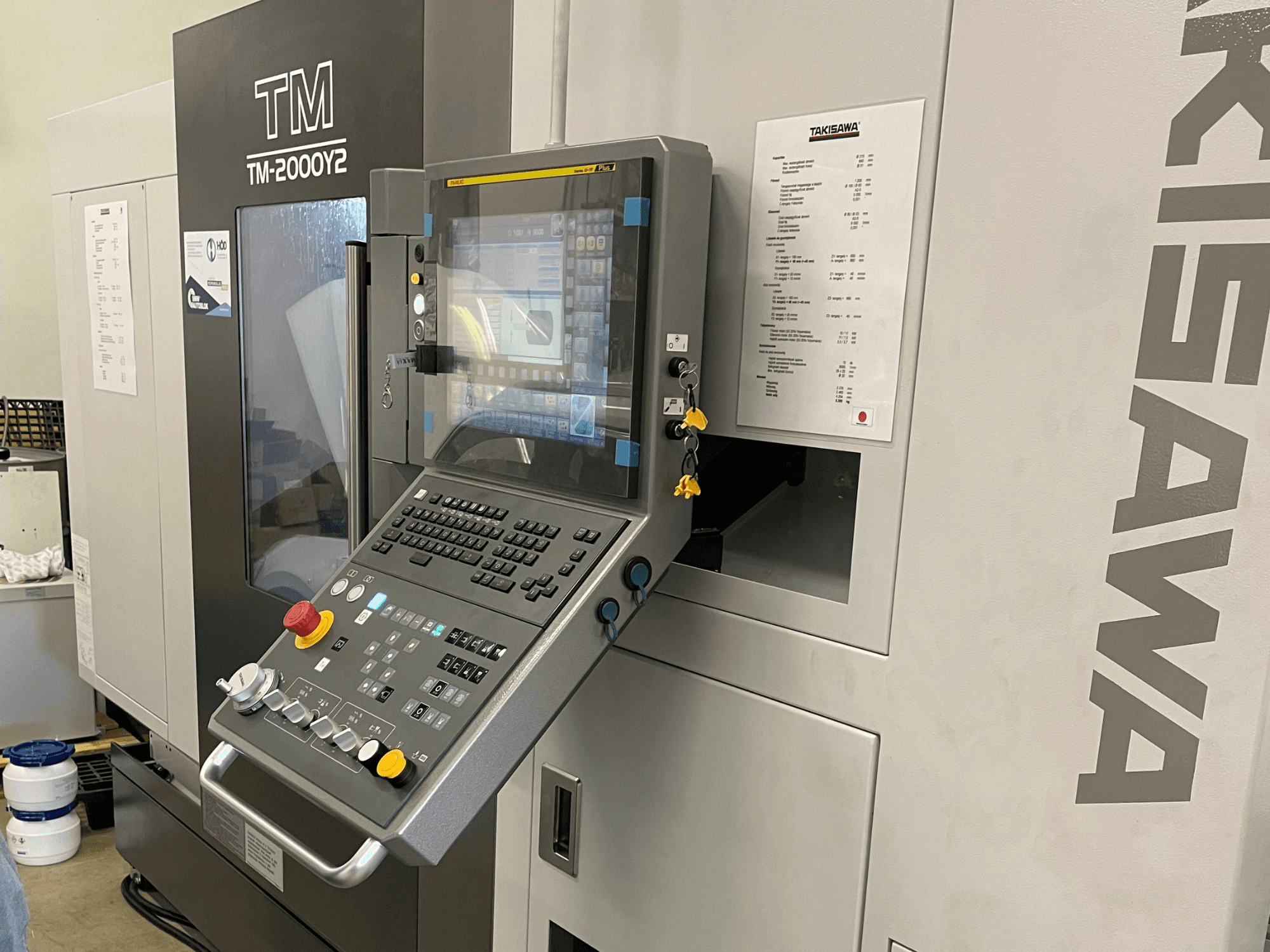 Takisawa TM-2000Y2 vízszintes esztergagép vezérlőpanelje elölnézetben, digitális kijelzővel és kezelőgombokkal.