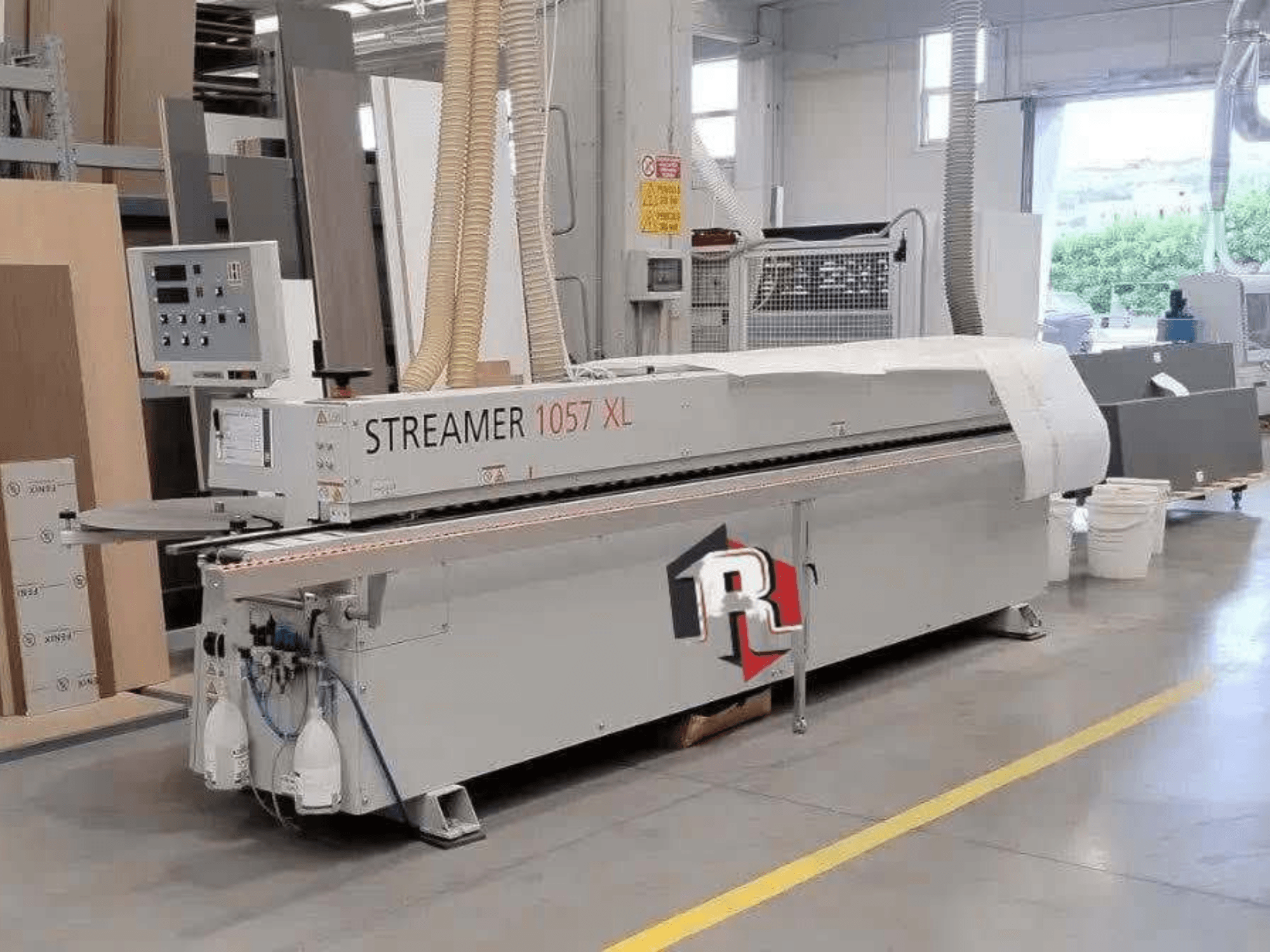 HOLZHER STREAMER 1057 XL élragasztó gép egy műhelyben, oldalnézetben, látható vezérlőpanellel és légtömlőkkel.