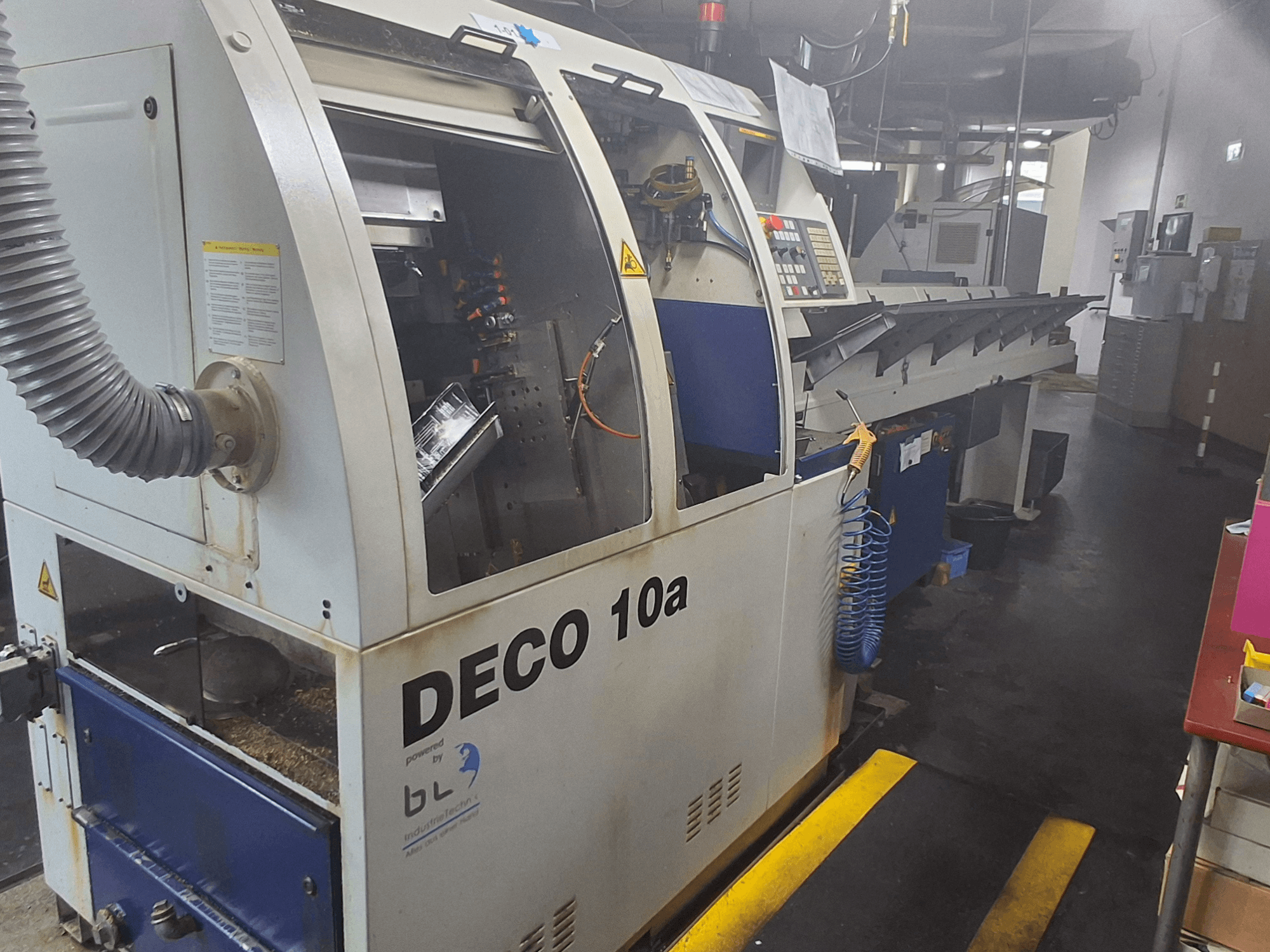 Svájci típusú esztergagép TORNOS DECO 10a, előlnézet; vezérlőpanel, látható mechanizmusok és porelszívó cső.