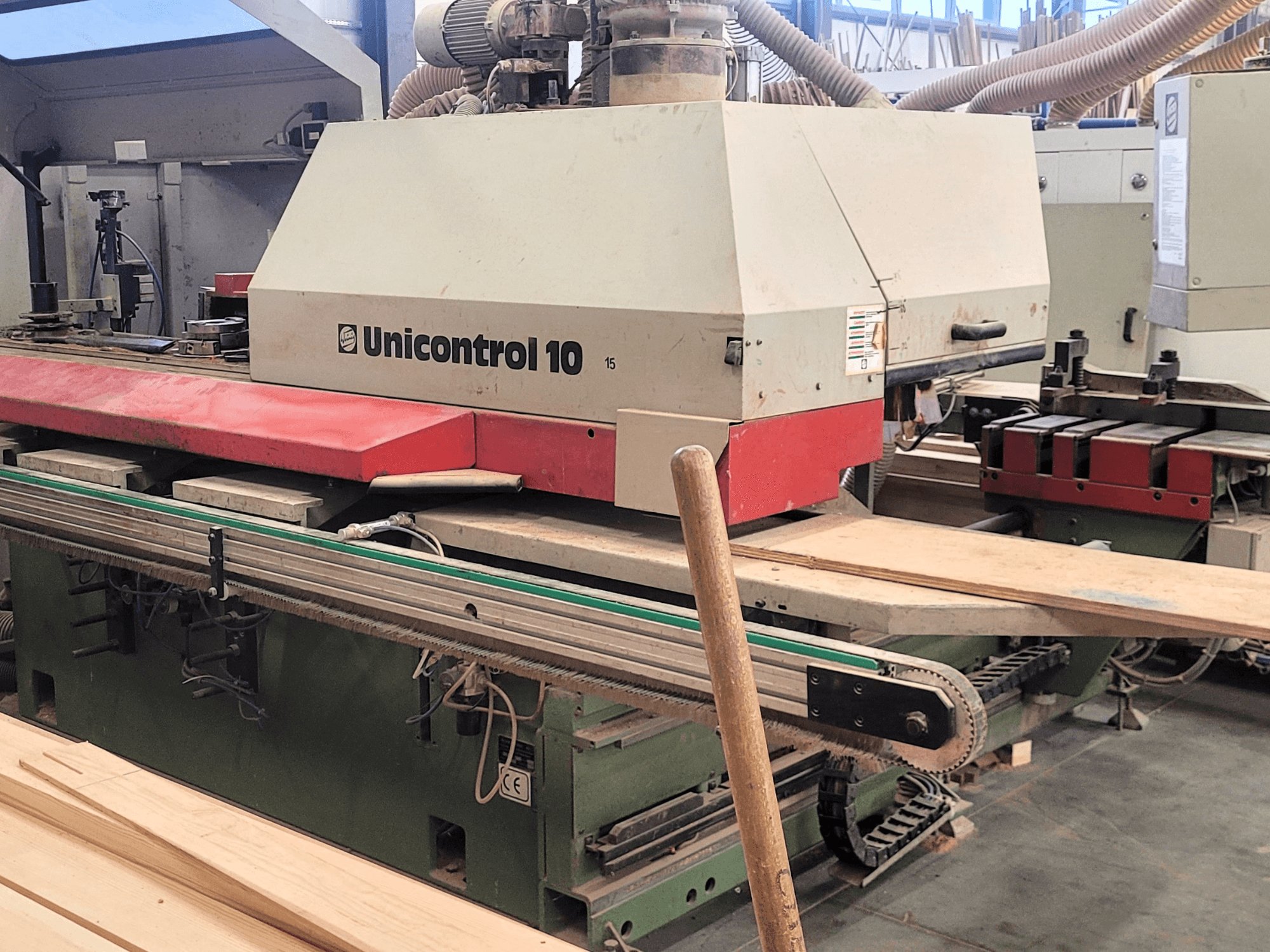 CNC megmunkálóközpont Unicontrol 10 by WEINIG/DIMTER, elölnézet, falapokkal és berendezésekkel műhelykörnyezetben.
