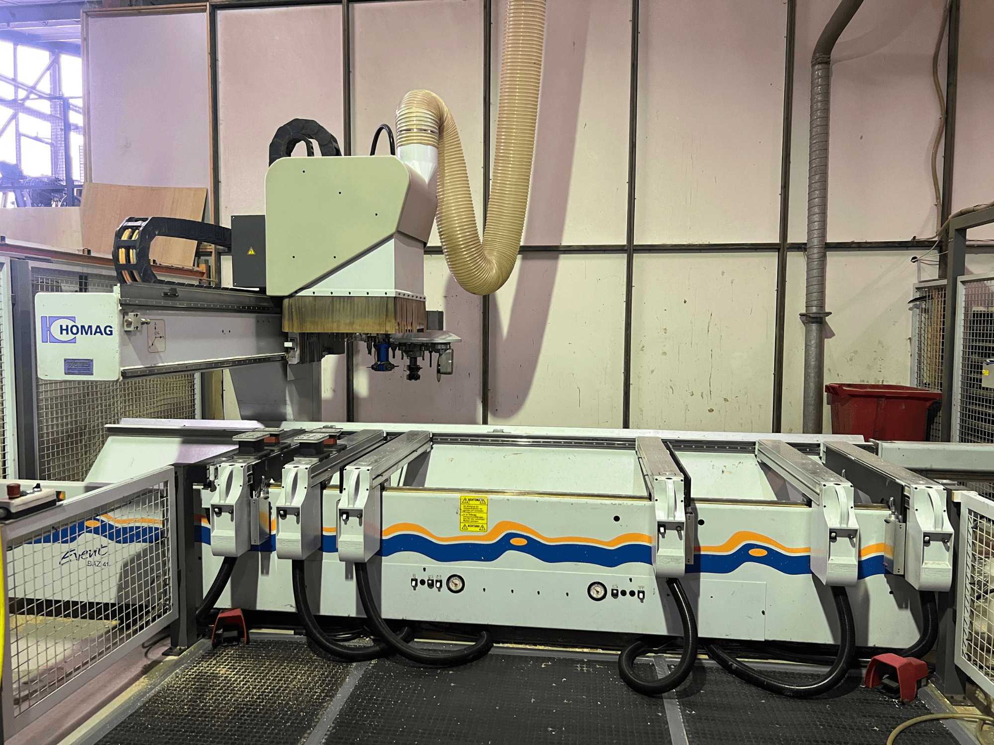 HOMAG BIZ 4 CNC-gép a műhelyben; elölnézetben a porelszívó rendszer és a vezérlőpanel a kábelekkel.