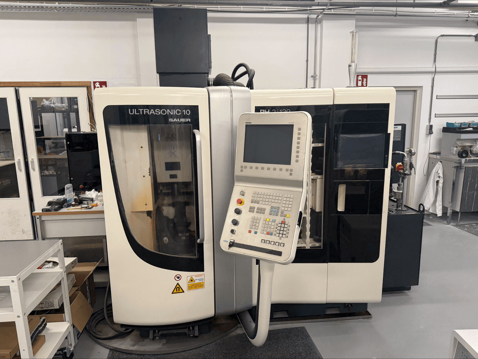 DMG Sauer Ultrasonic 10 + PH 2 | 120 függőleges megmunkálóközpont, elölnézetben, vezérlőpanel és nagyméretű ablak.