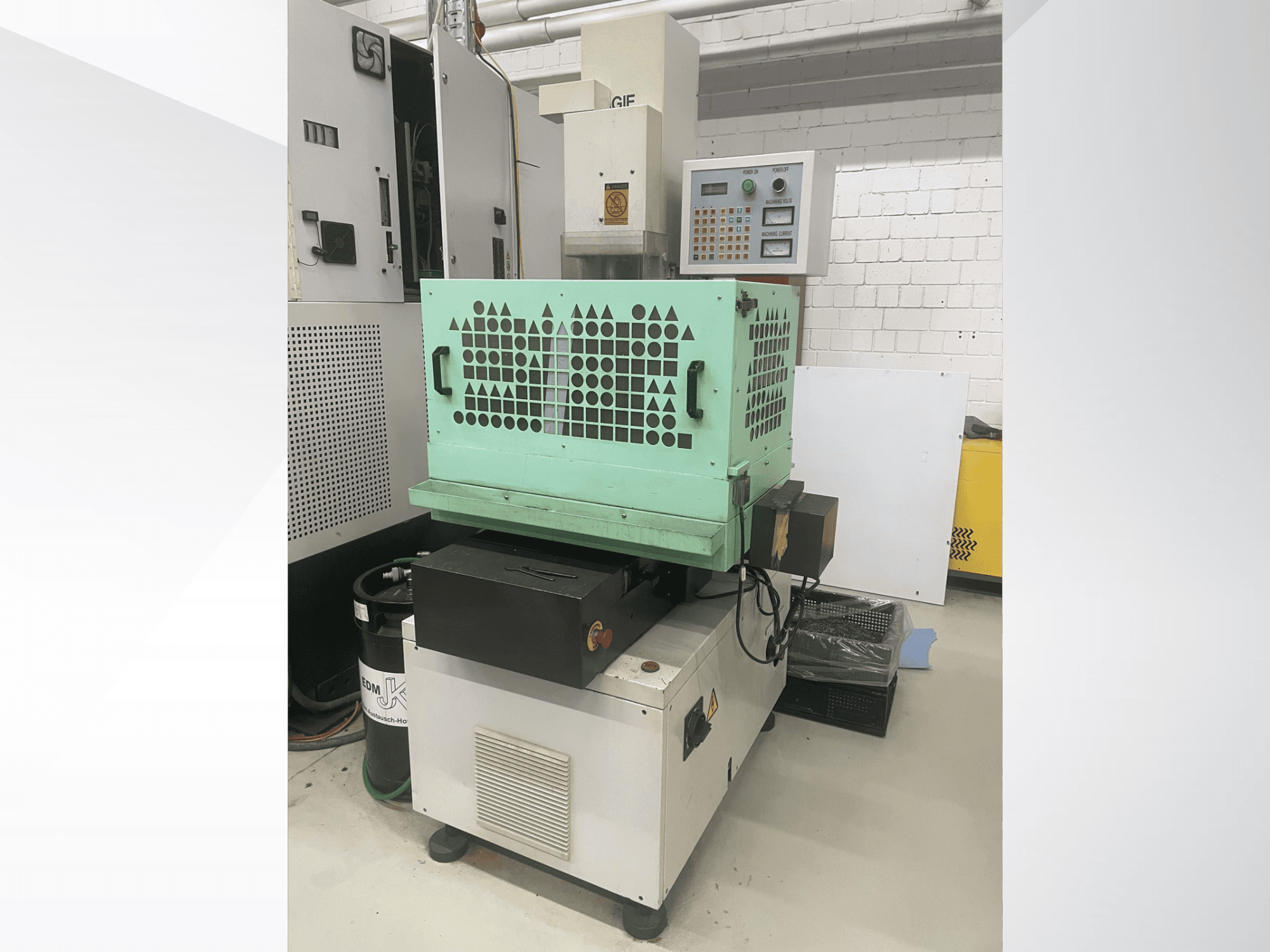 AGIE Drill, fém fúrógép, elölnézetből látható a vezérlés, a zöld burkolat és a kompakt kialakítás. Ideális precíziós munkákhoz.