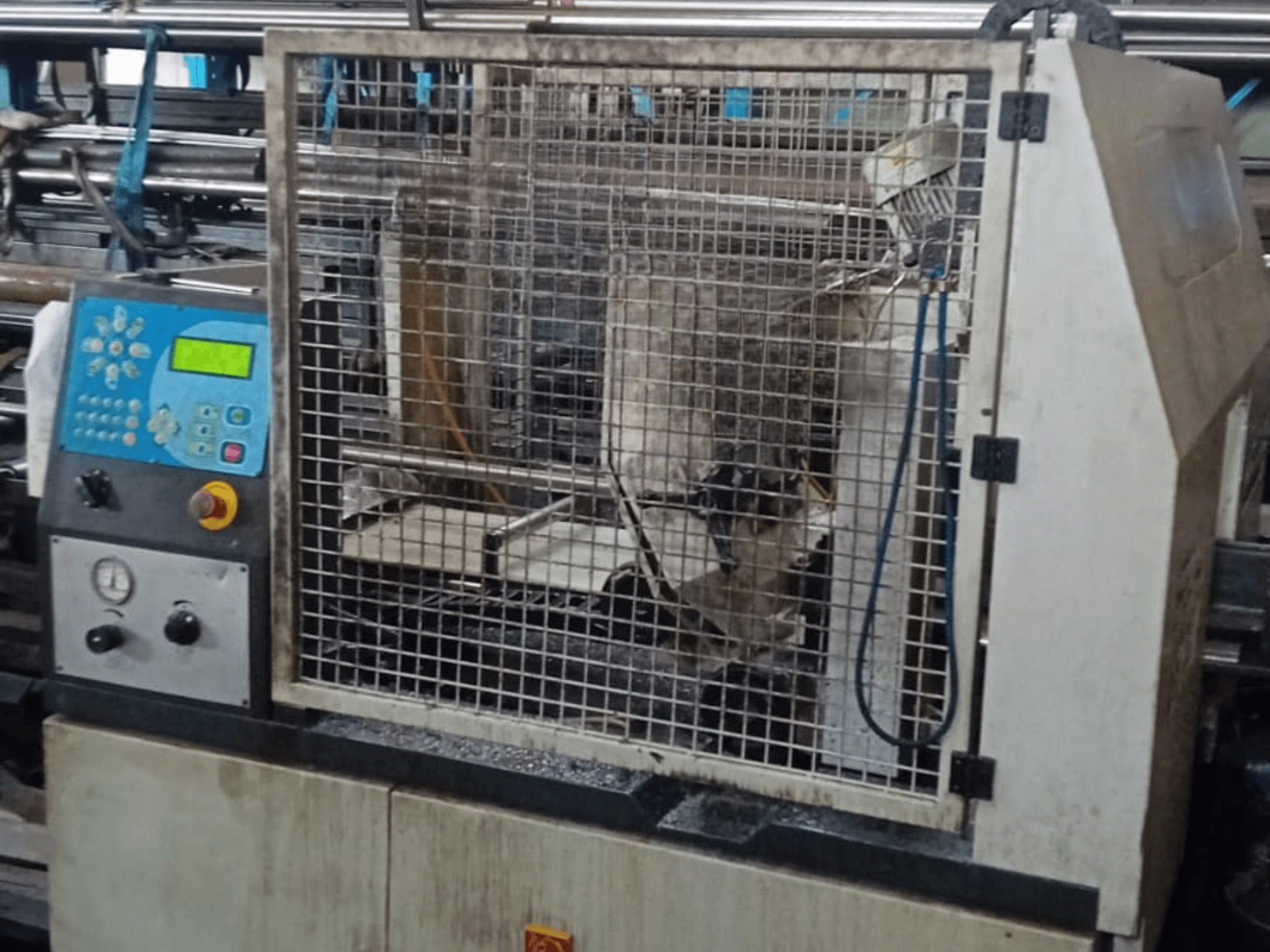 Fém szalagfűrész Macc 381 AV, elölnézet, a vezérlőpanel, a biztonsági ketrec és a fémtörmelék az alapon.