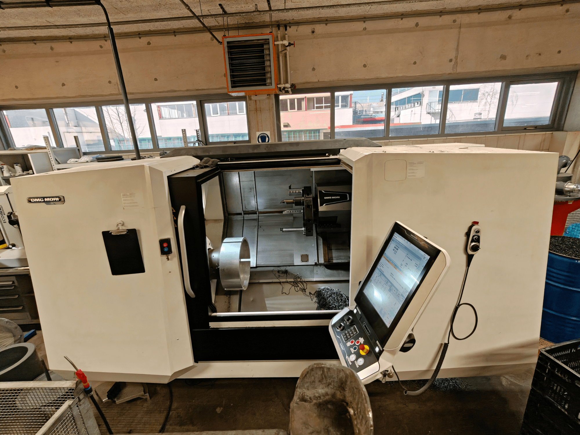 Egy DMG MORI CLX 550 vízszintes esztergagép elülső nézete, a vezérlőpanel és a nyitott munkaterület bemutatása.