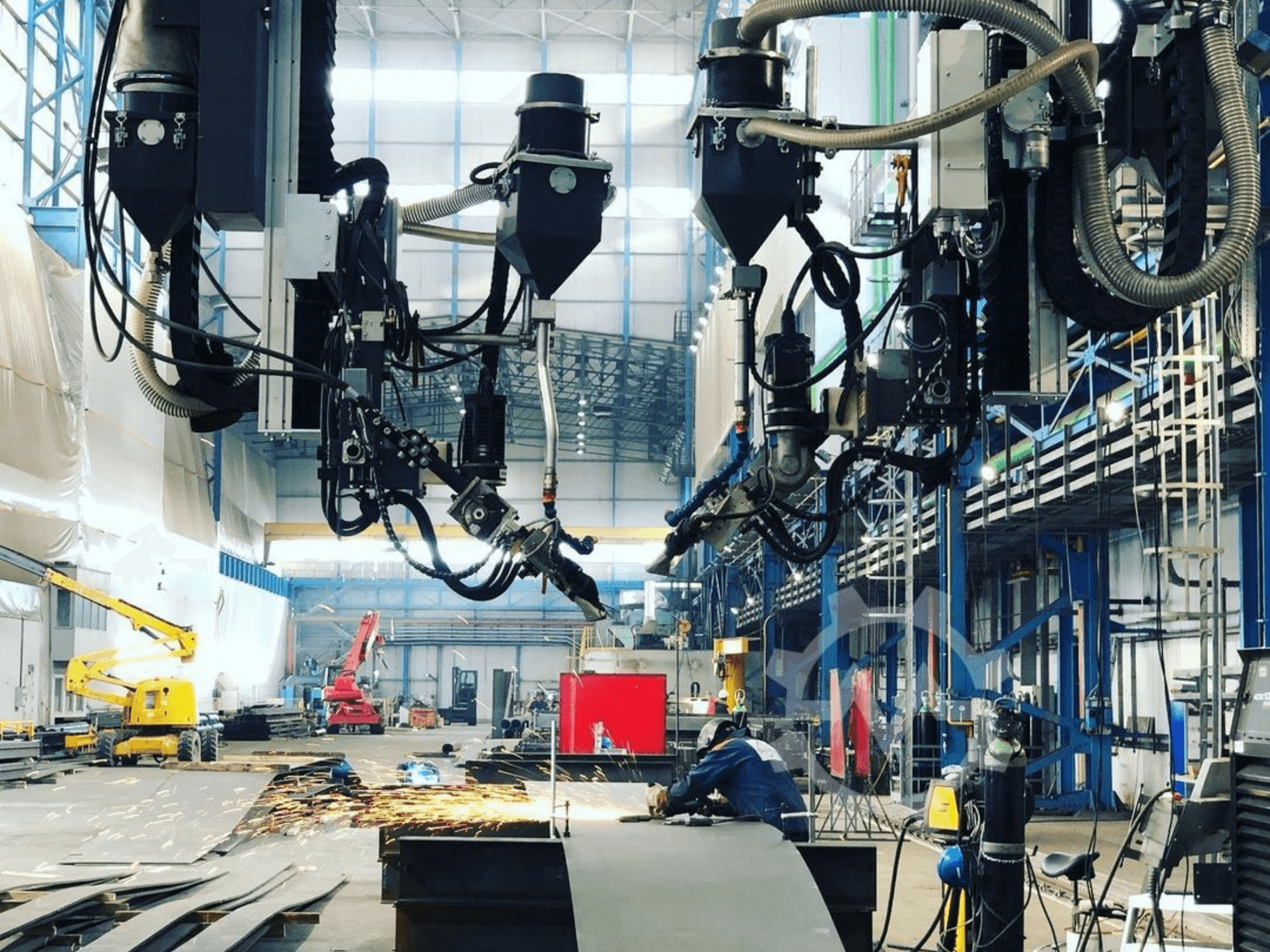 Robotizált vágógép ipari környezetben, szikrázó szikrákkal, oldalról nézve; több tartozékkal és tömlőkkel.