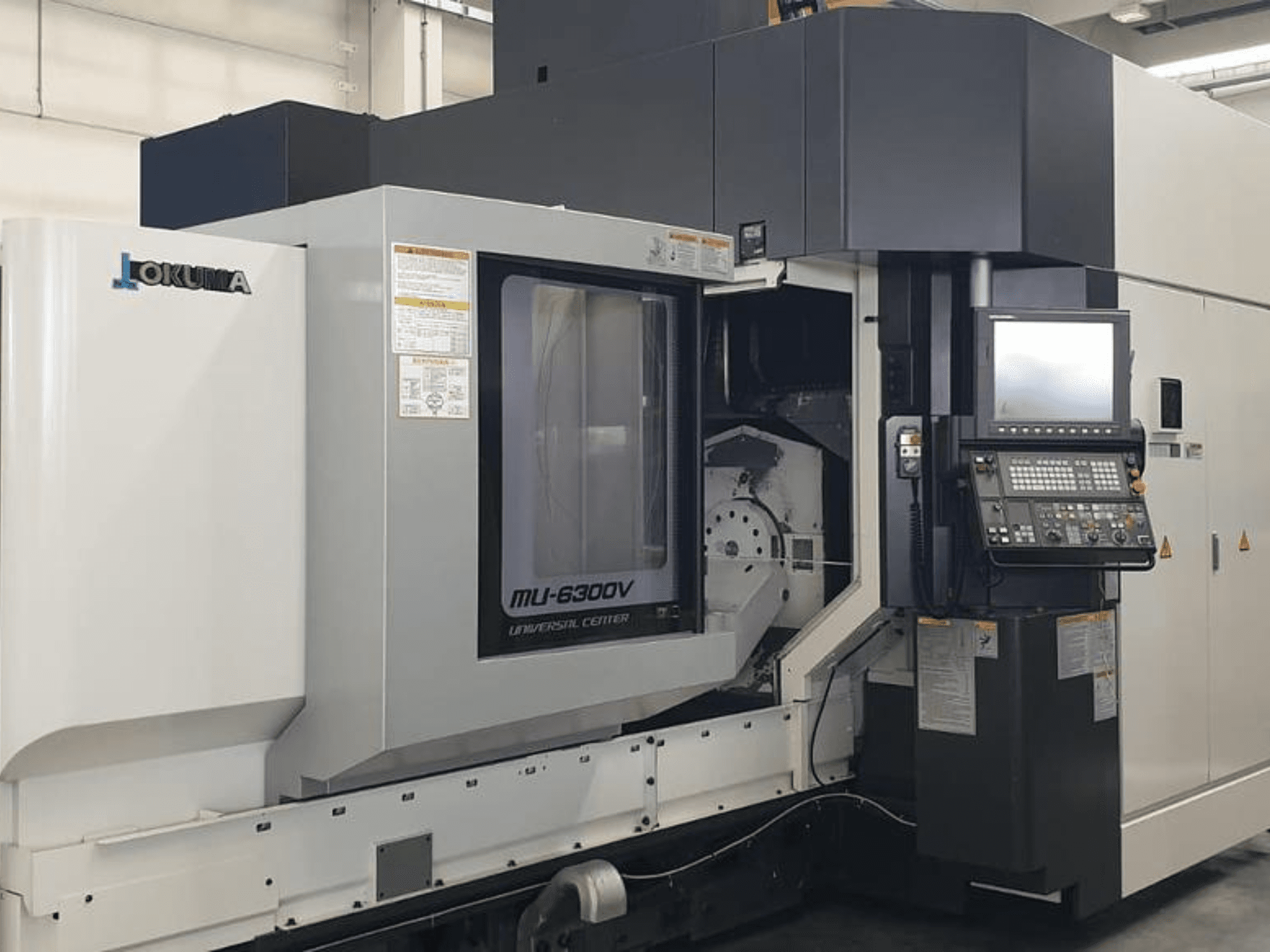 Okuma MU 6300 V függőleges megmunkálóközpont, előlnézet a vezérlőpanel és a megmunkálási terület részleteivel.