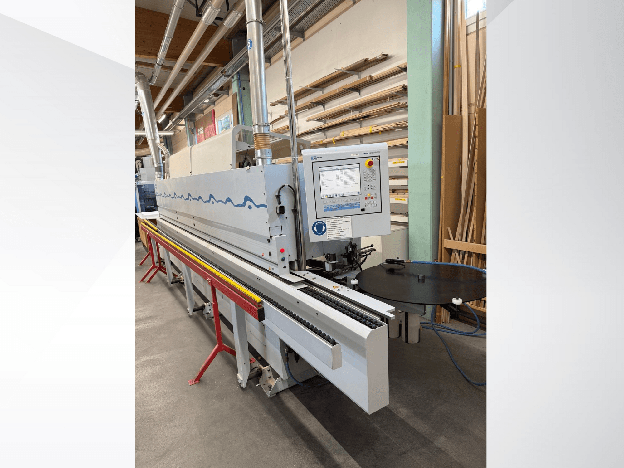 Egy HolzHer automata élszalagozó gép előlnézetből, vezérlőpanellel, szállítórendszerrel és kerek tartóasztallal.