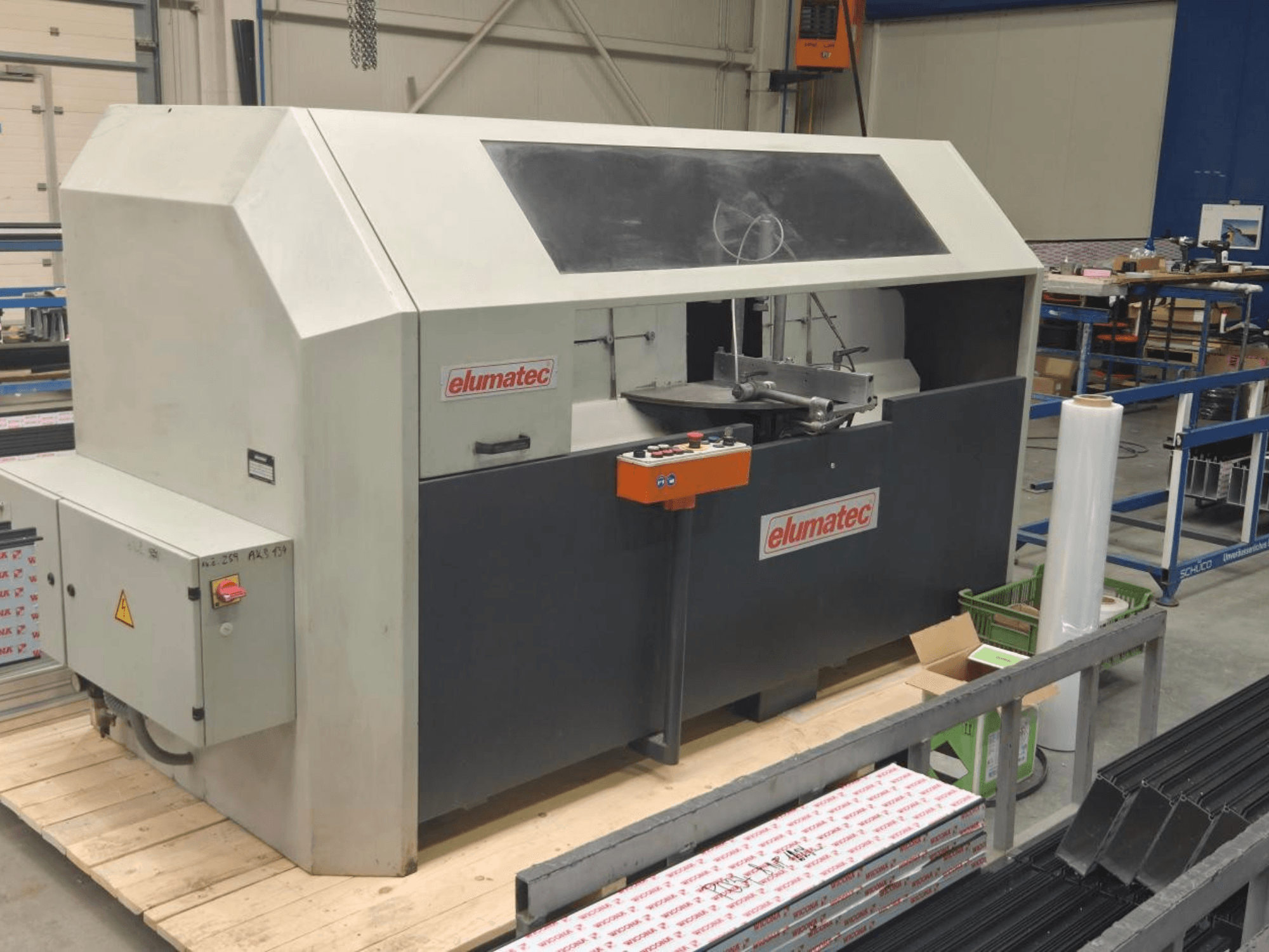 Elumatec AKS 134 fém körfűrész, elölnézet, a kezelőpanel és a vágási terület bemutatása egy faplatformon.