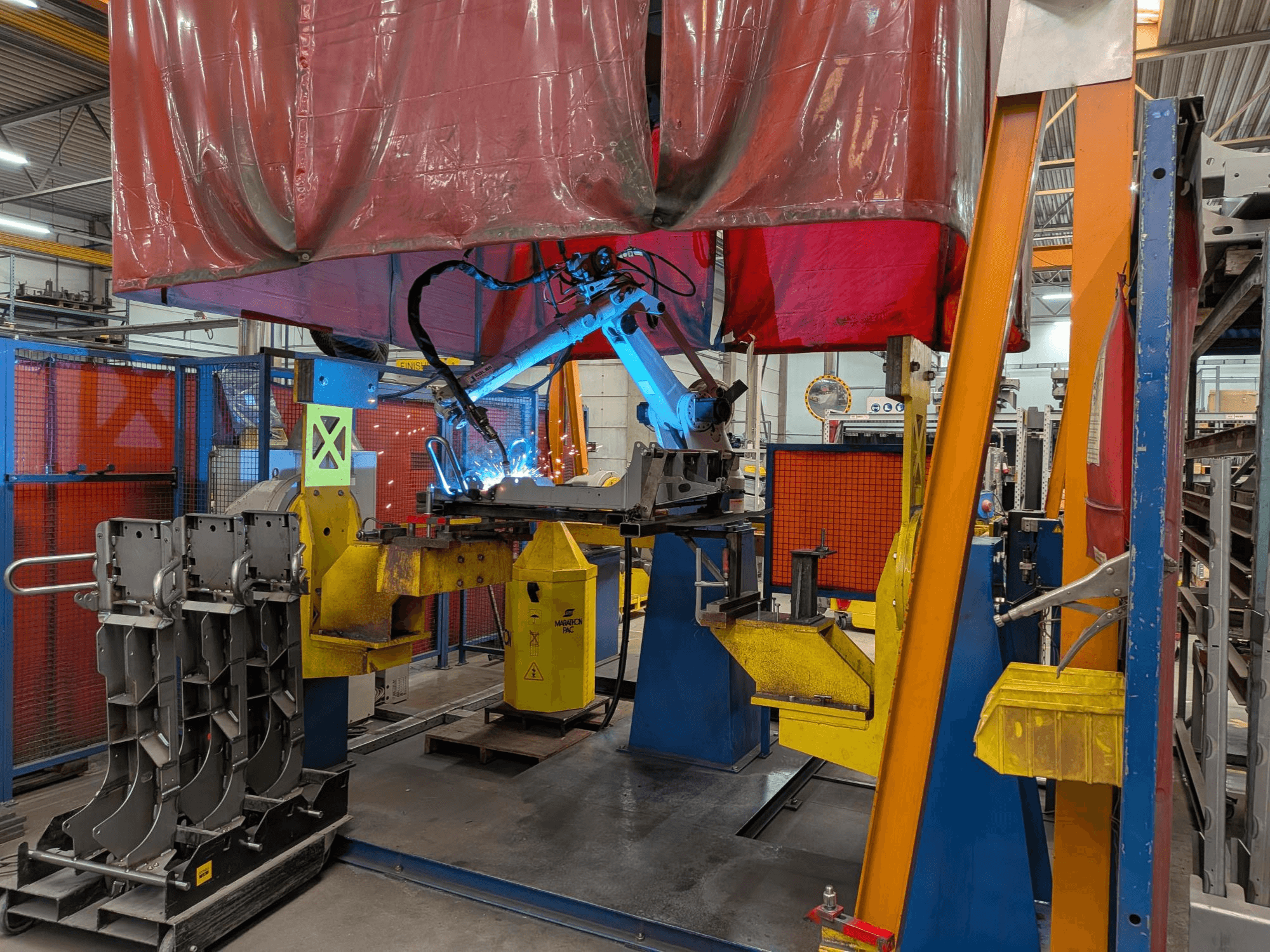 Az OTC Daihen DR4200 hegesztőrobot működés közben, elölről nézve, élénk kék hegesztőívvel és védőburkolattal.