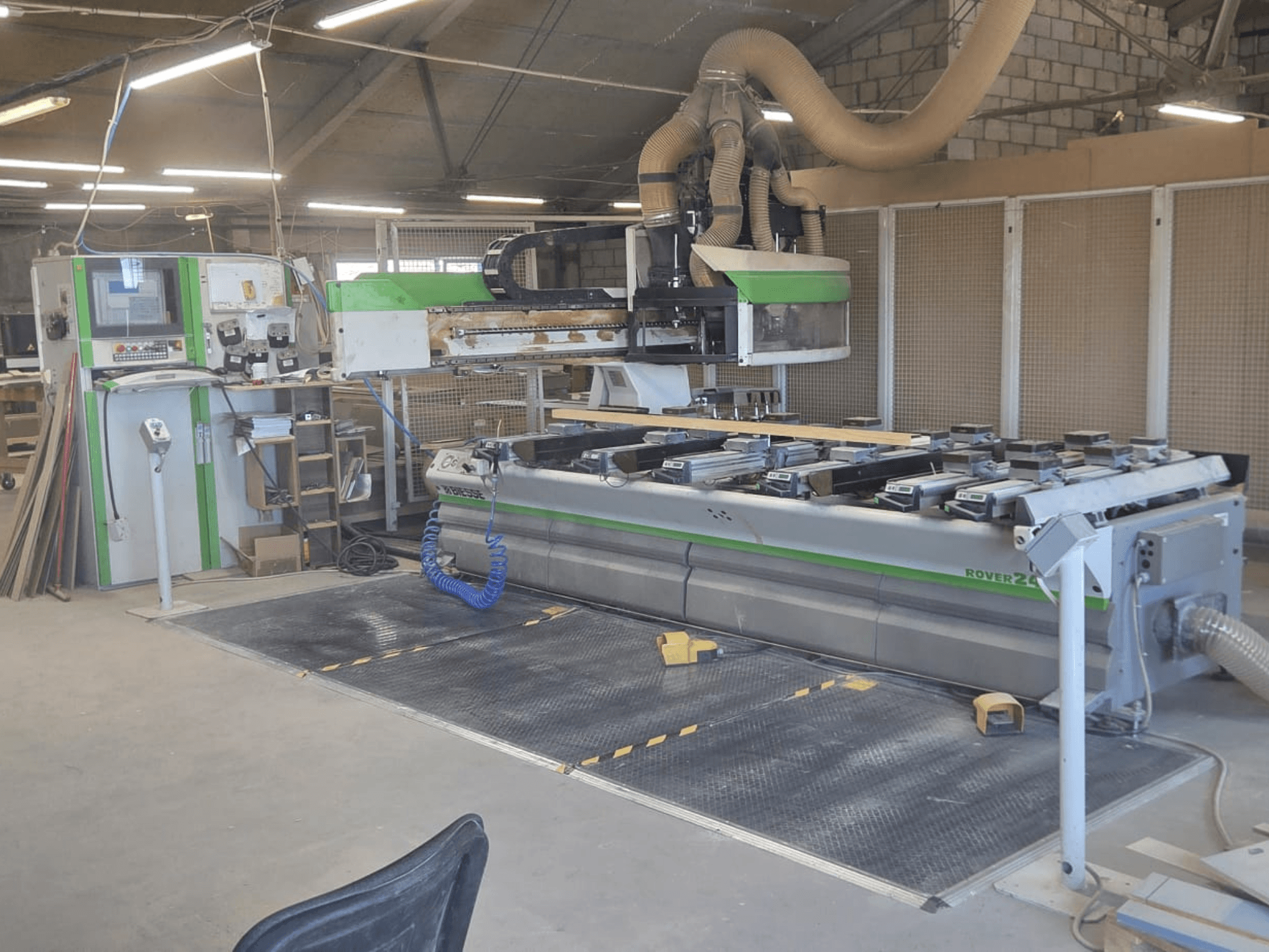 CNC megmunkáló központ BIESSE Rover 24S egy műhelyben, vezérlőpult és nagy munkafelület fadarabokkal.
