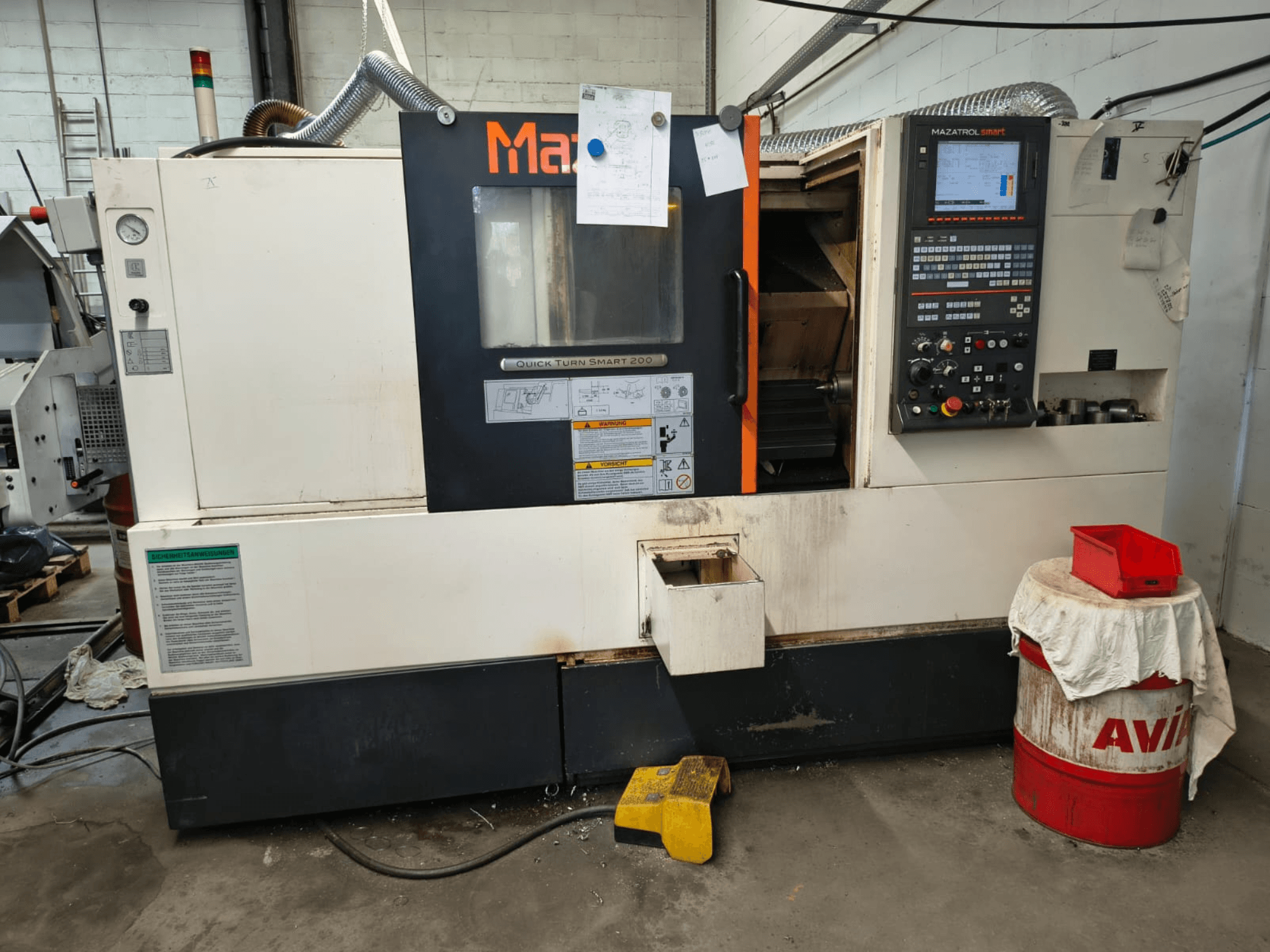 Mazak Quick Turn Smart 200, vízszintes eszterga, elölnézet, amelyen látható a vezérlőpanel, a hűtőfolyadék-tartály és a jelölések.