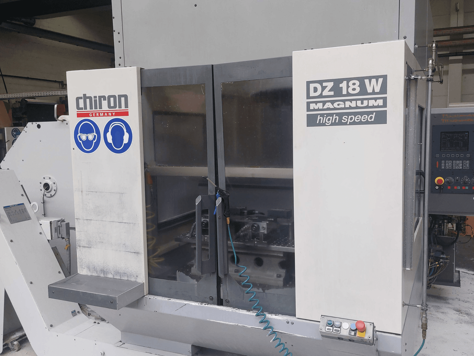 CHIRON DZ 18 W MAGNUM függőleges megmunkáló központ, elölnézet a vezérlőpanellel és a biztonsági jelzésekkel.