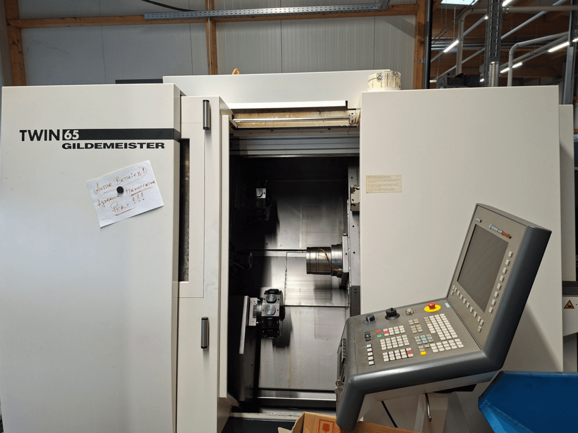 Gildemeister TWIN 65 CNC eszterga, elölnézetben a vezérlőpanel és a részben nyitott kamra a látható gépekkel.
