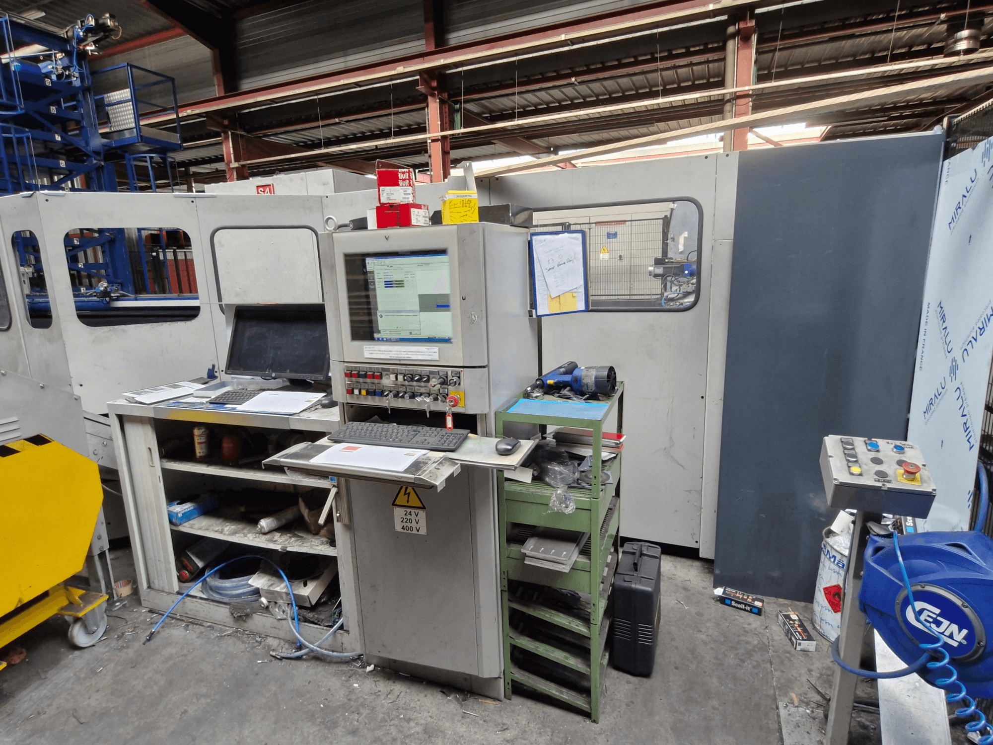 CNC lyukasztógép Salvagnini S4-40 egy műhelyben, vezérlőpult monitorokkal és szerszámokkal, elölnézetben.