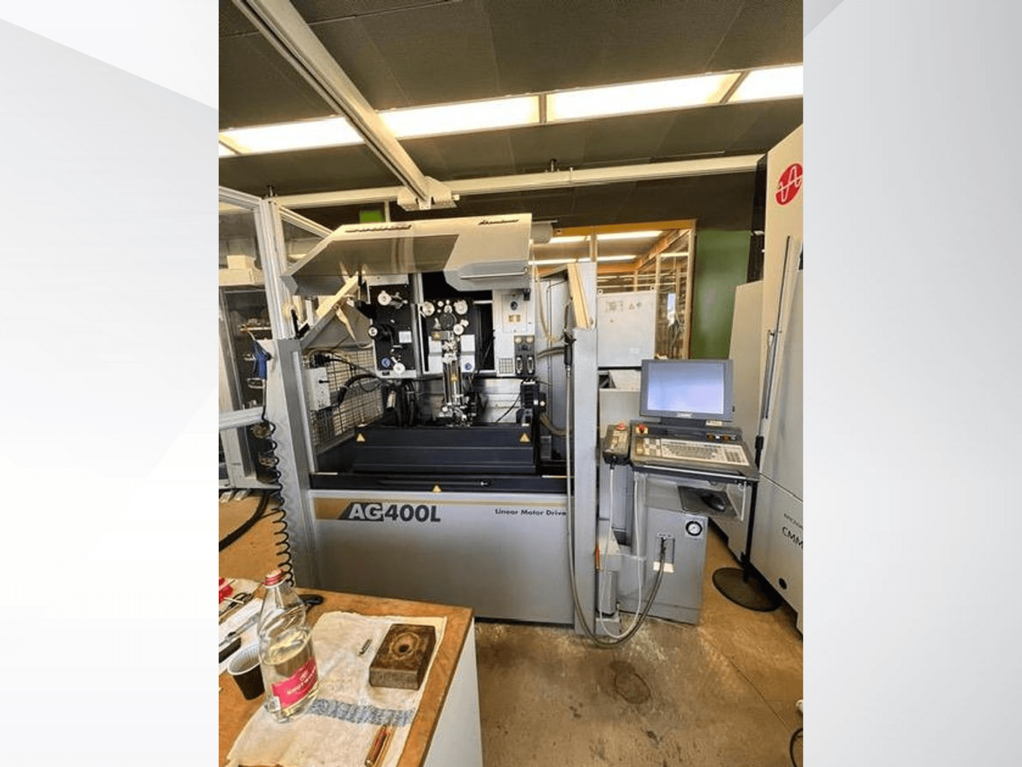 AG400L lineáris motoros meghajtású gép, elölnézetben, a vezérlőpanel és a munkaterület látható biztonsági elemekkel.